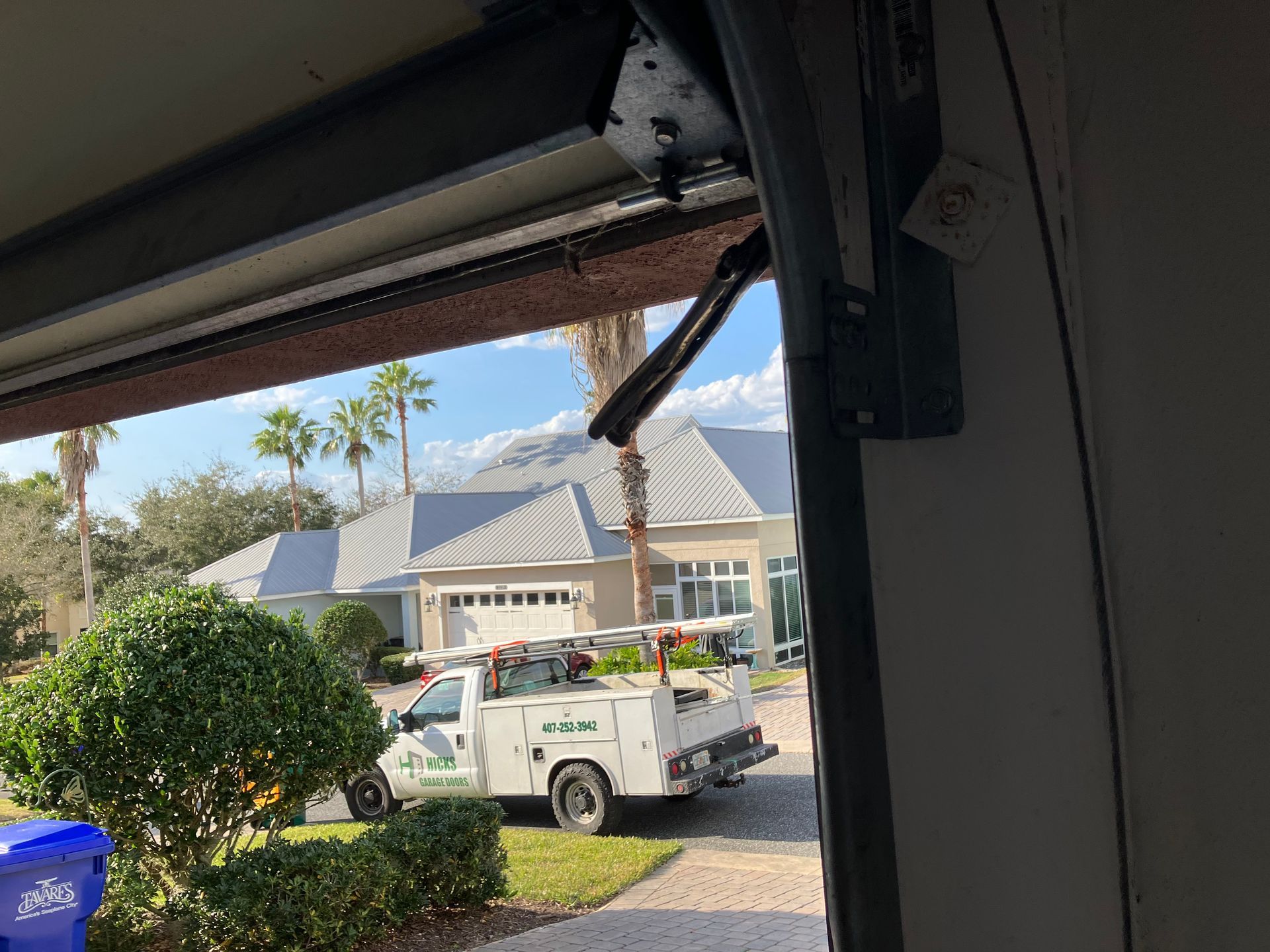 View from a garage to a suburban house with a white utility truck parked in the driveway.