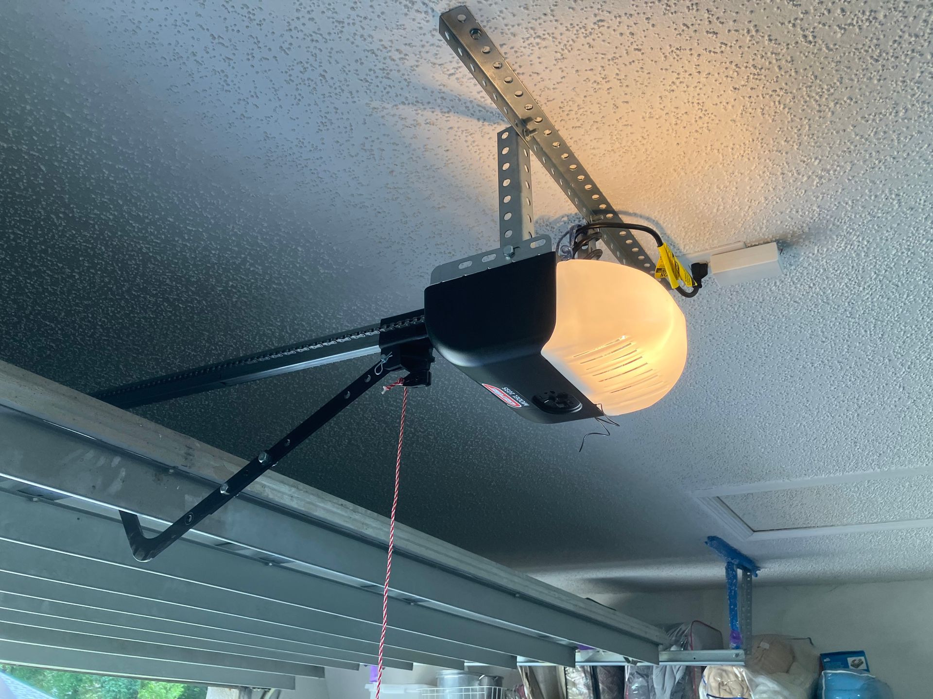 Garage ceiling with an open garage door opener and rail mechanism, lit by a warm bulb