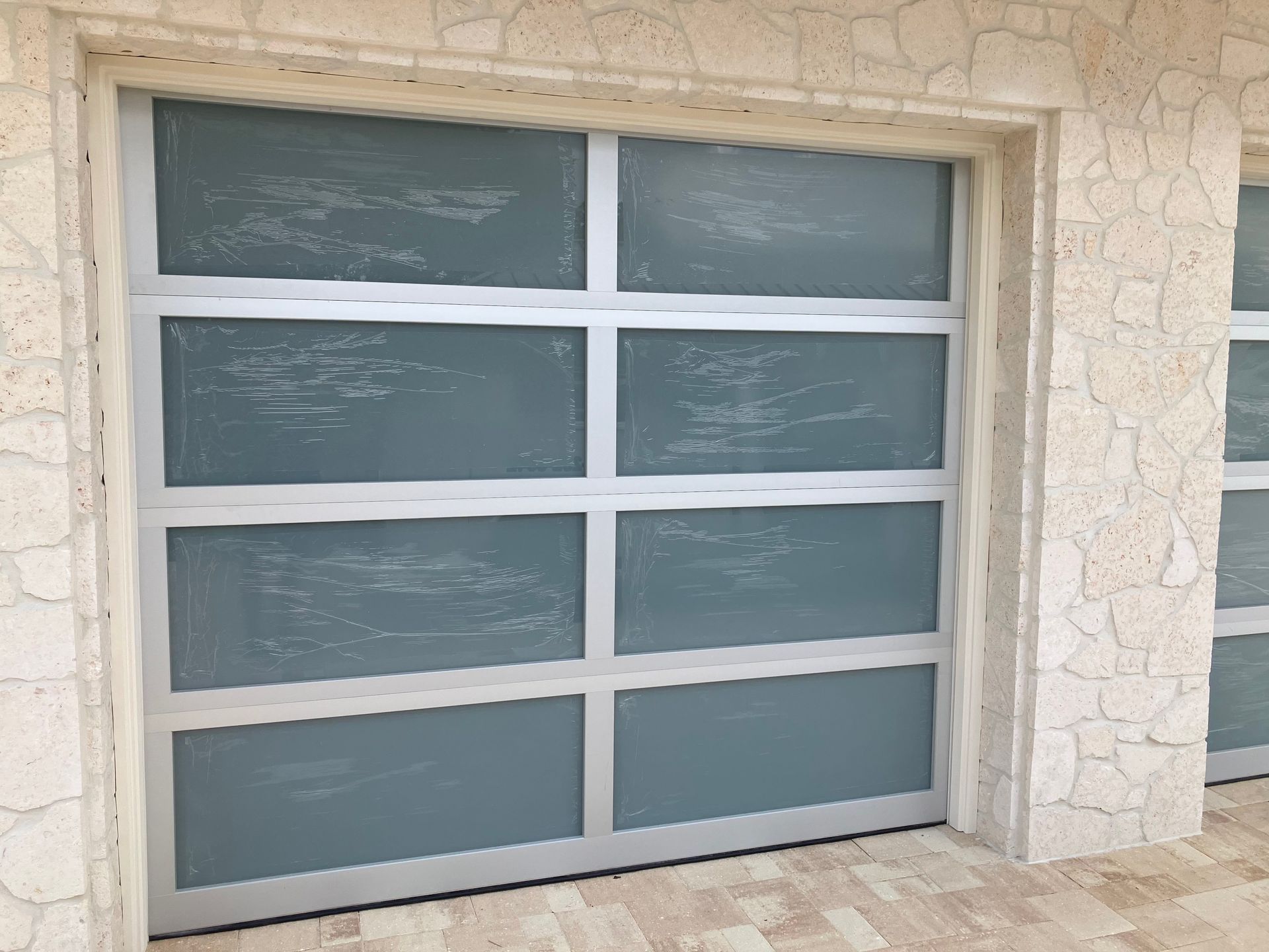 Closed frosted-glass garage door in a beige stone exterior wall
