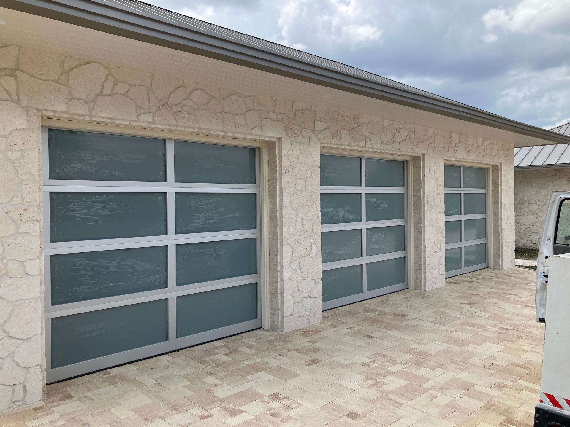 Modern house exterior with two gray garage doors and a stone facade