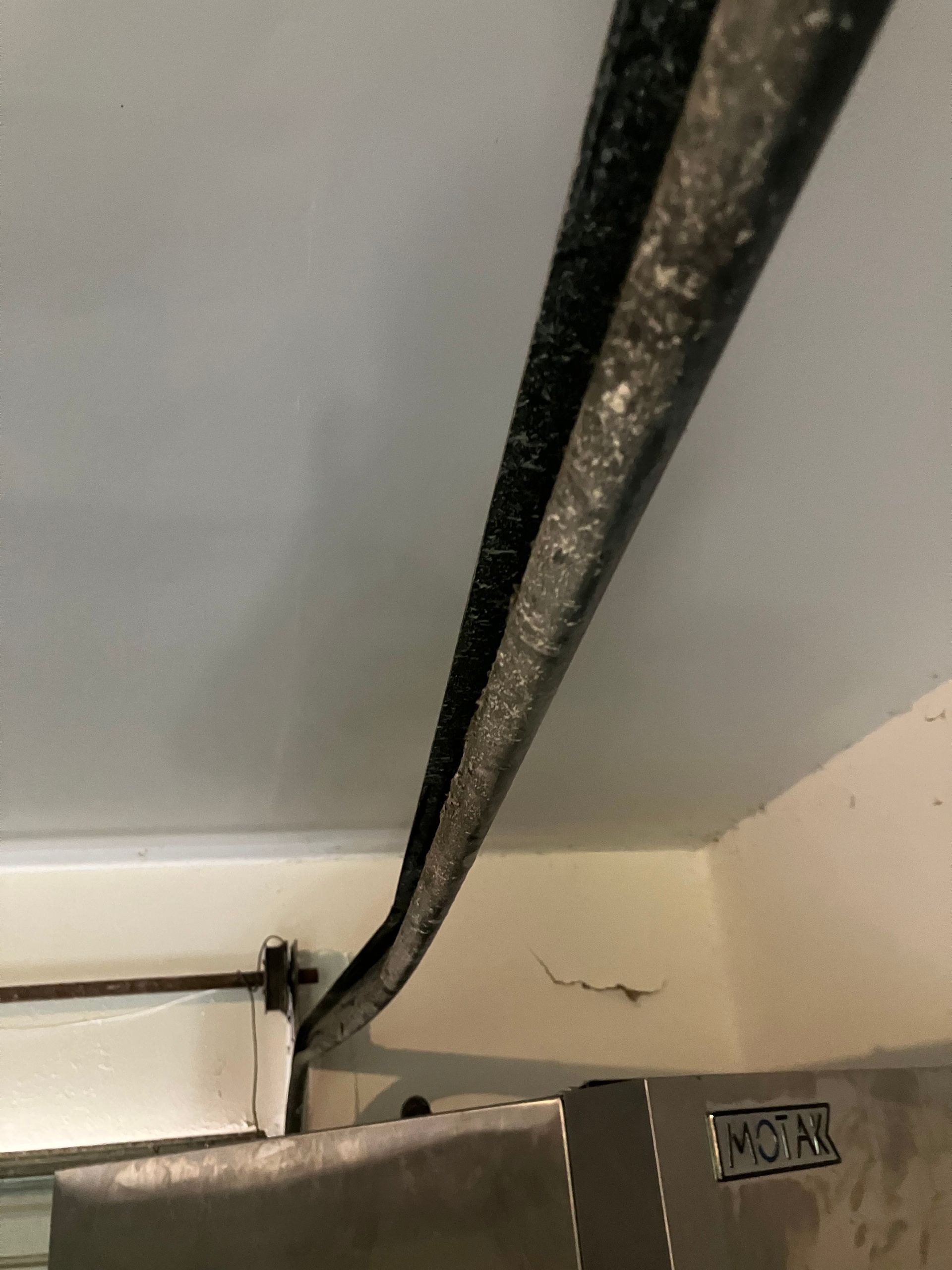 Ceiling corner with a black strap or cable running diagonally along the wall.