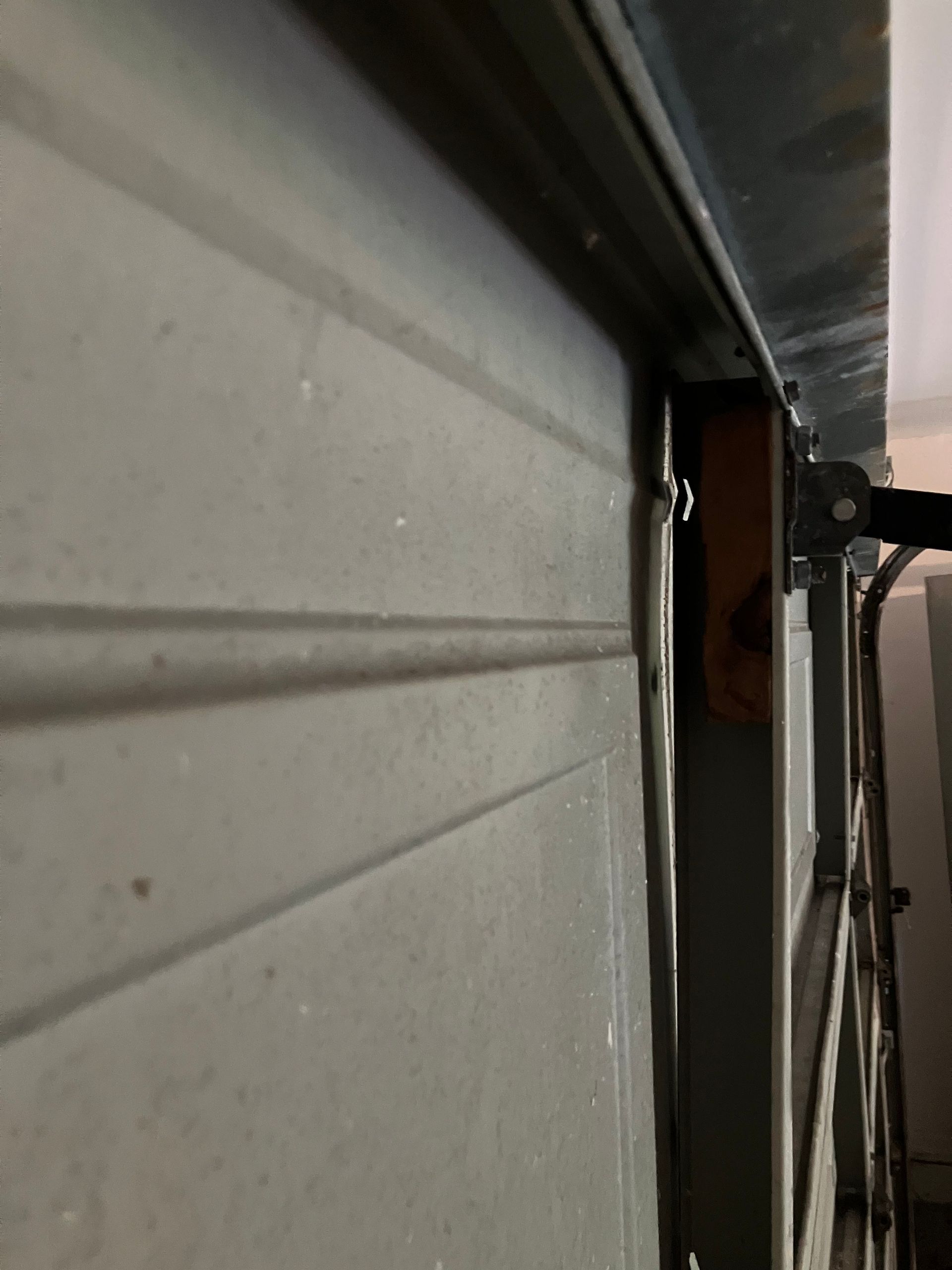 Close-up of a white garage door with a dark metal track and frame at the edge of a doorway.