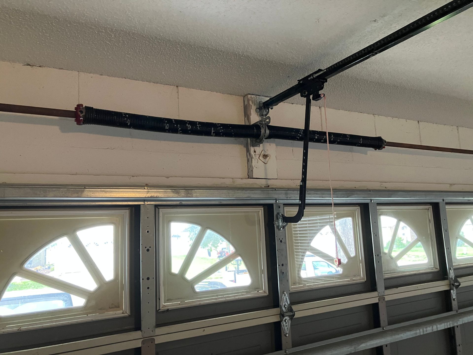 Garage door opener rail and hanging cord above a row of garage windows.