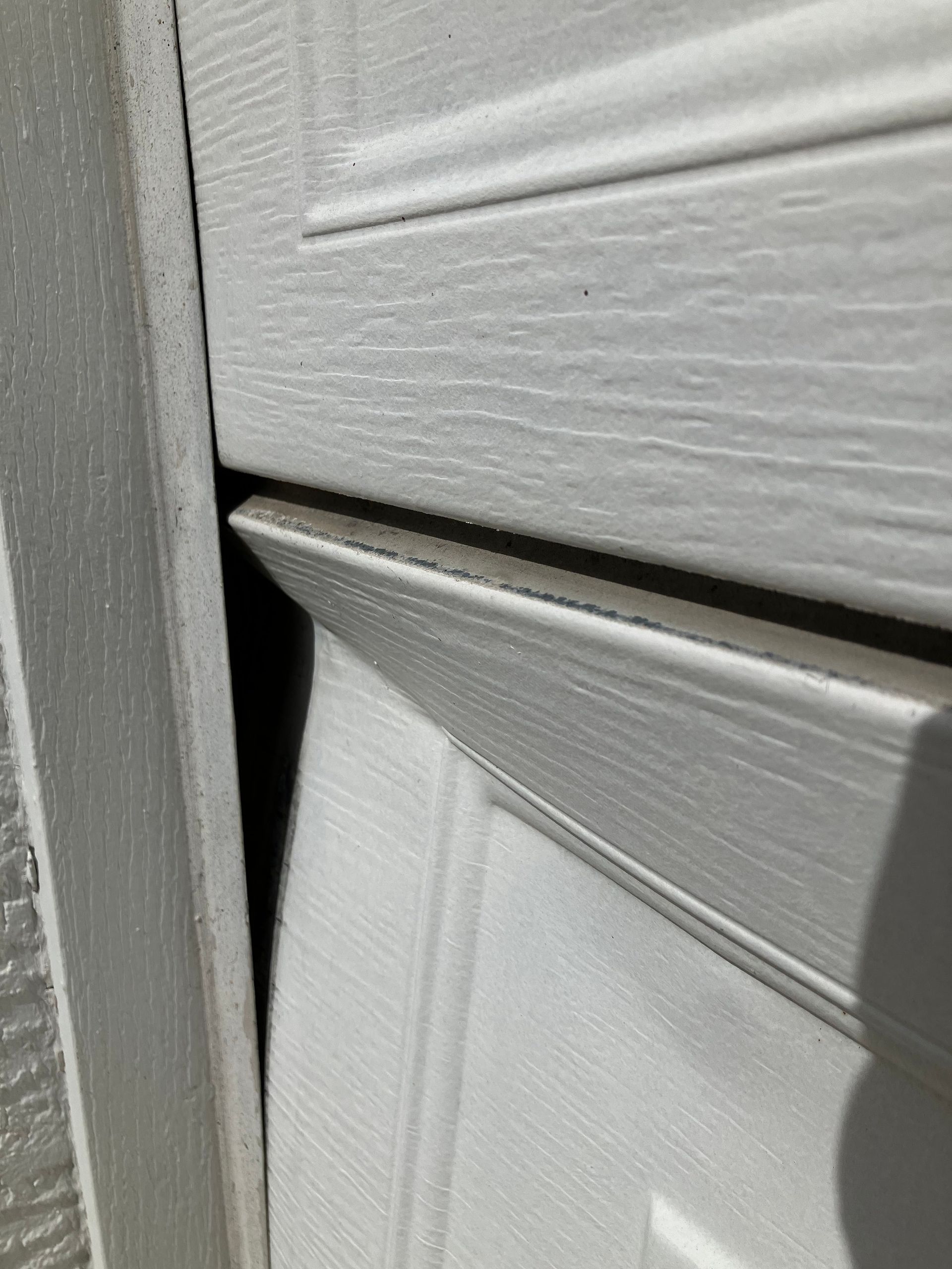 Close-up of white painted siding panels with a narrow gap between them