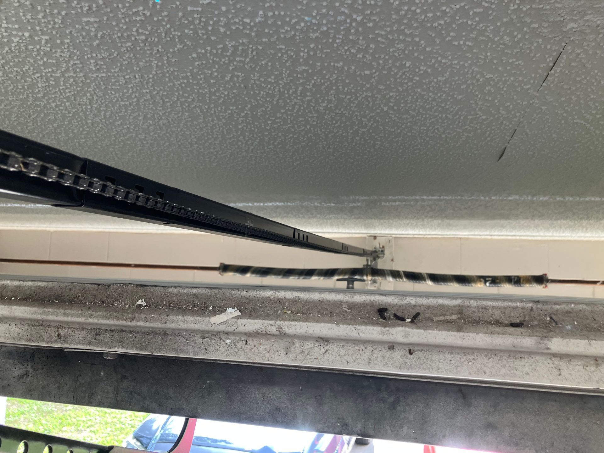 Damaged garage door track with a bent rail and debris along the ceiling frame