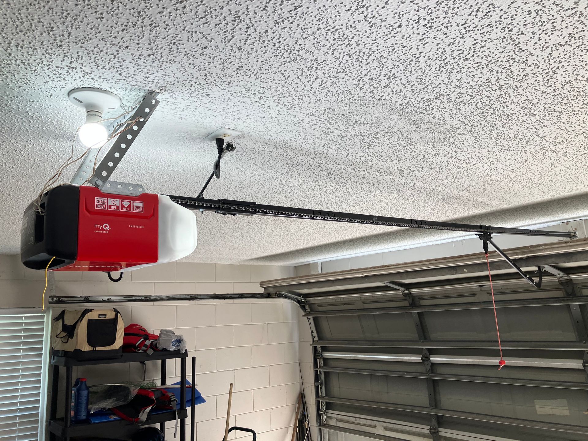 Garage ceiling with a red-and-white garage door opener and metal tracks above a closed door