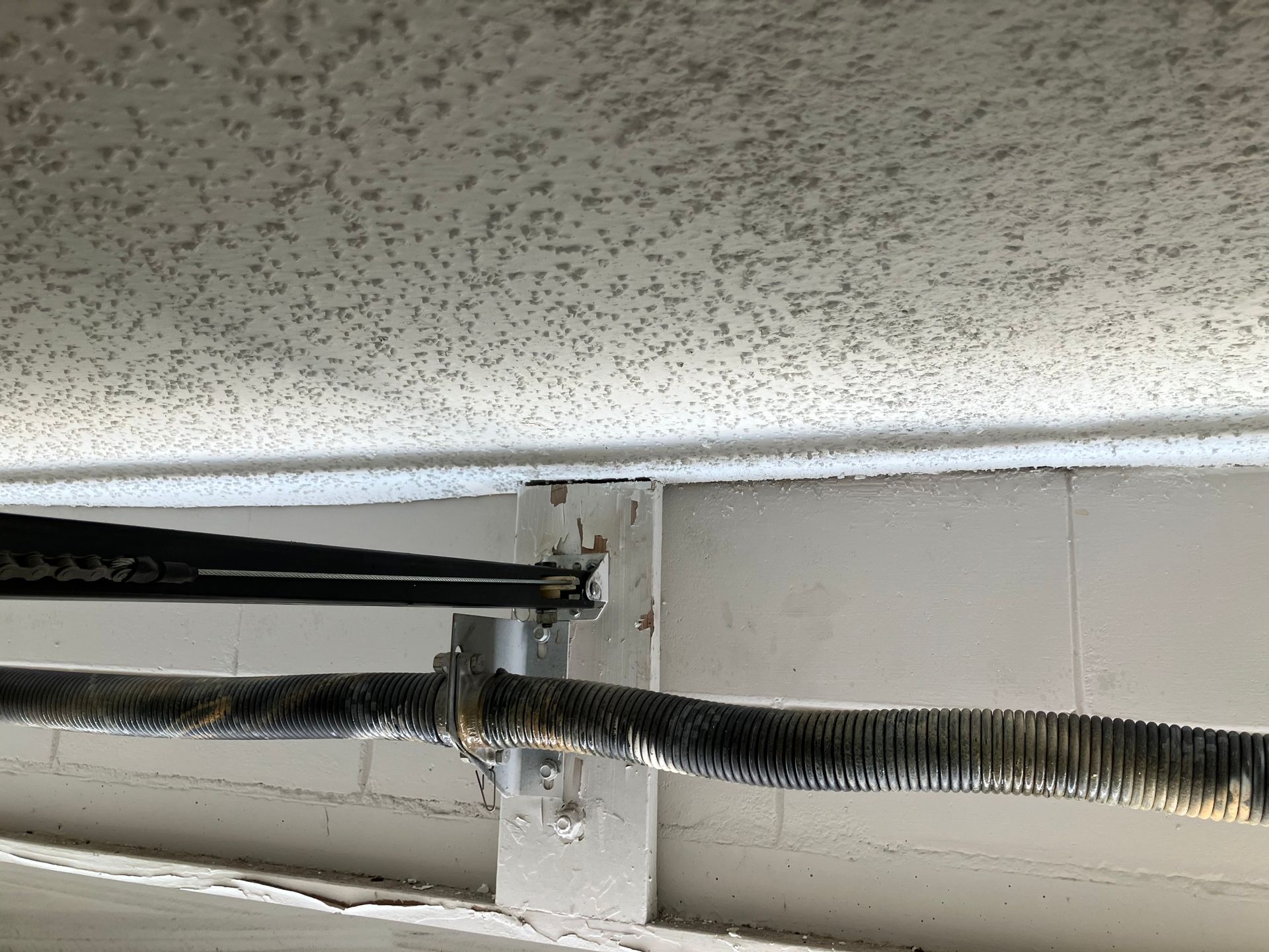 Exposed black and silver insulated cables running along a ceiling seam