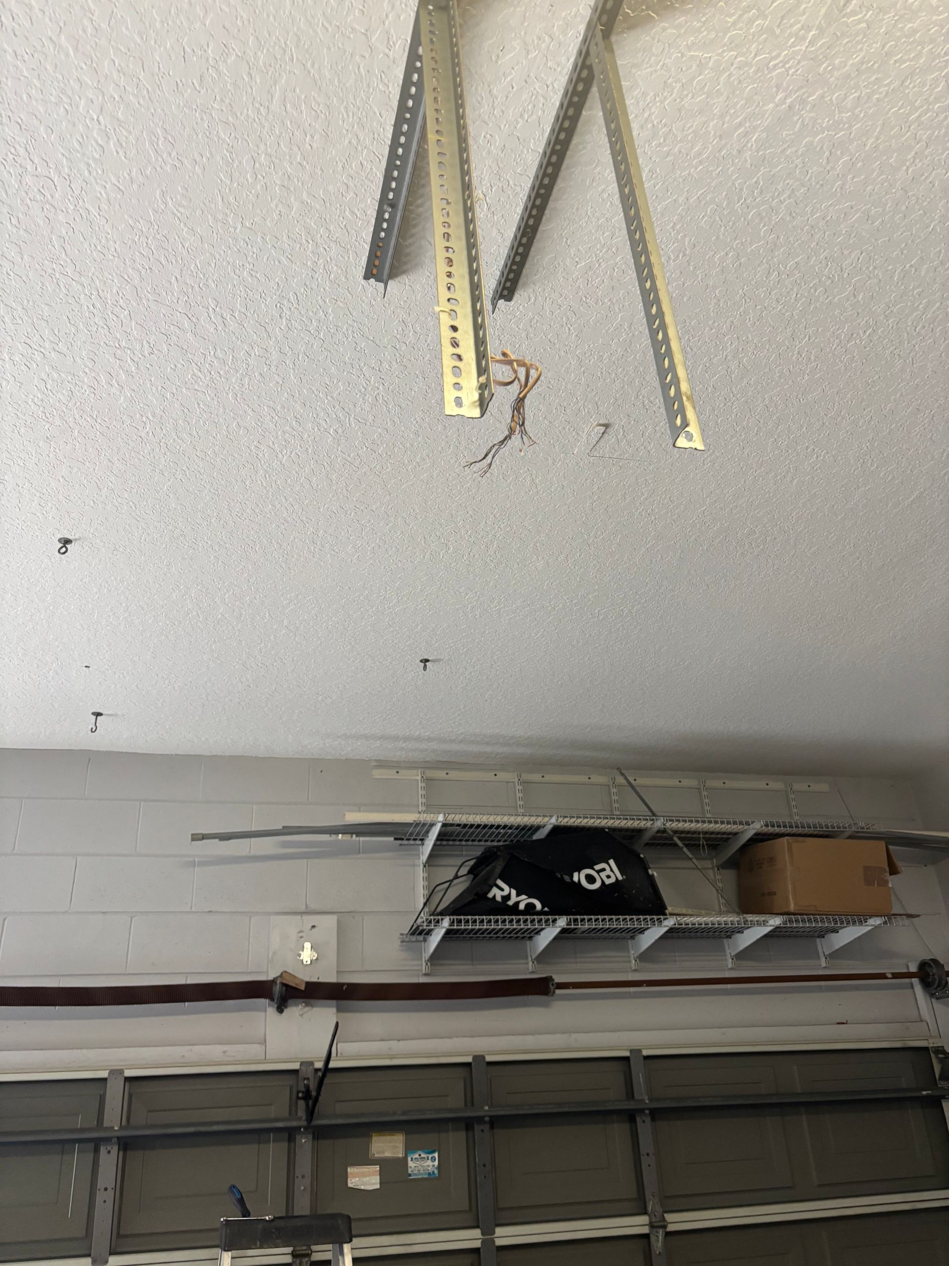 Garage ceiling with hanging metal tracks and storage shelves above a closed garage door