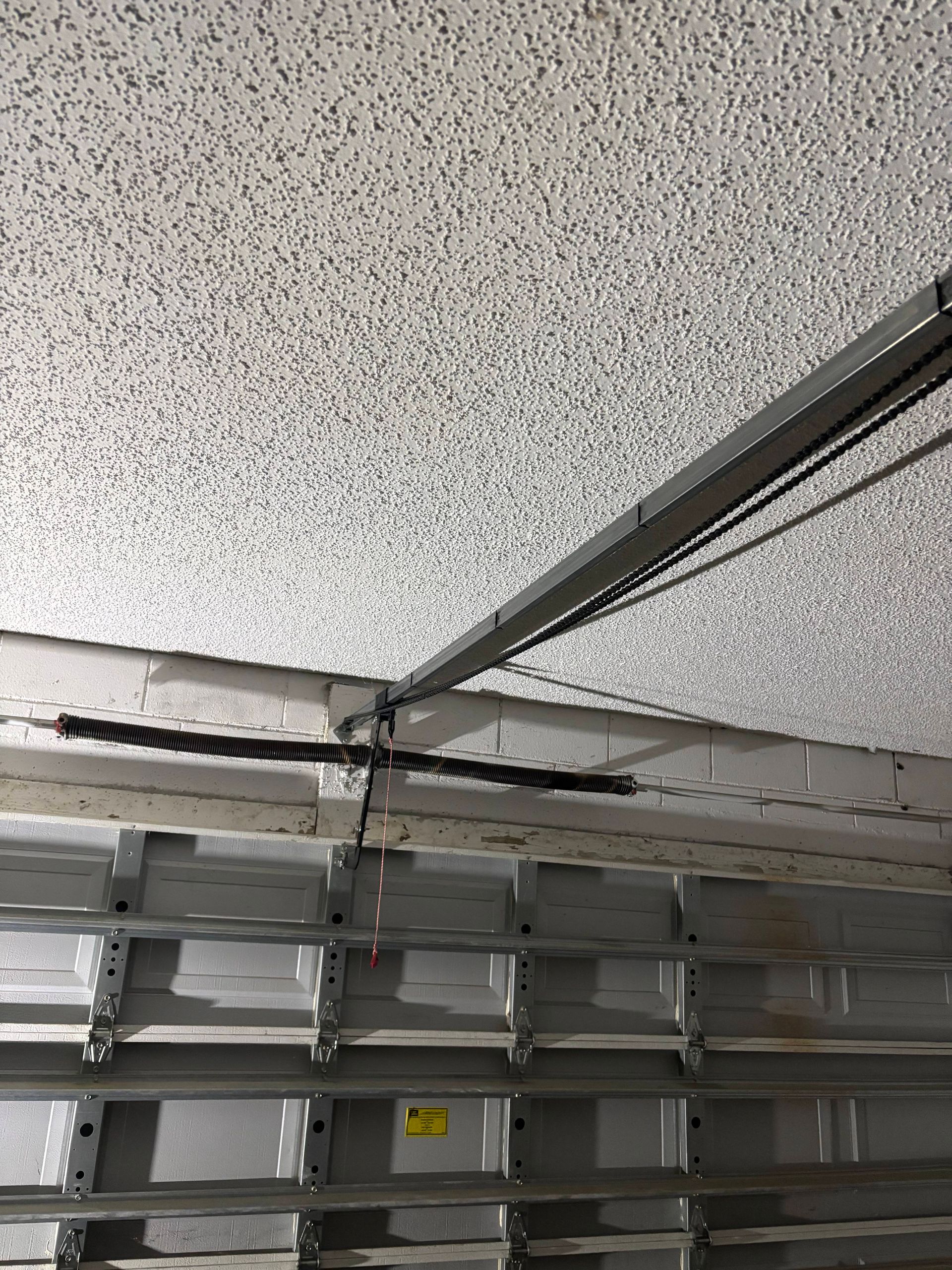 Ceiling-mounted garage door track and opener above stacked metal storage shelves