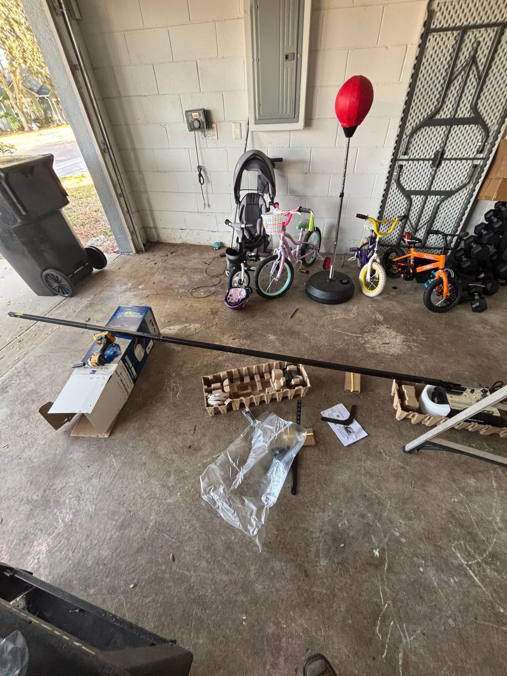 Garage with several children’s bikes and parts scattered on the floor, including a red balloon and tools.