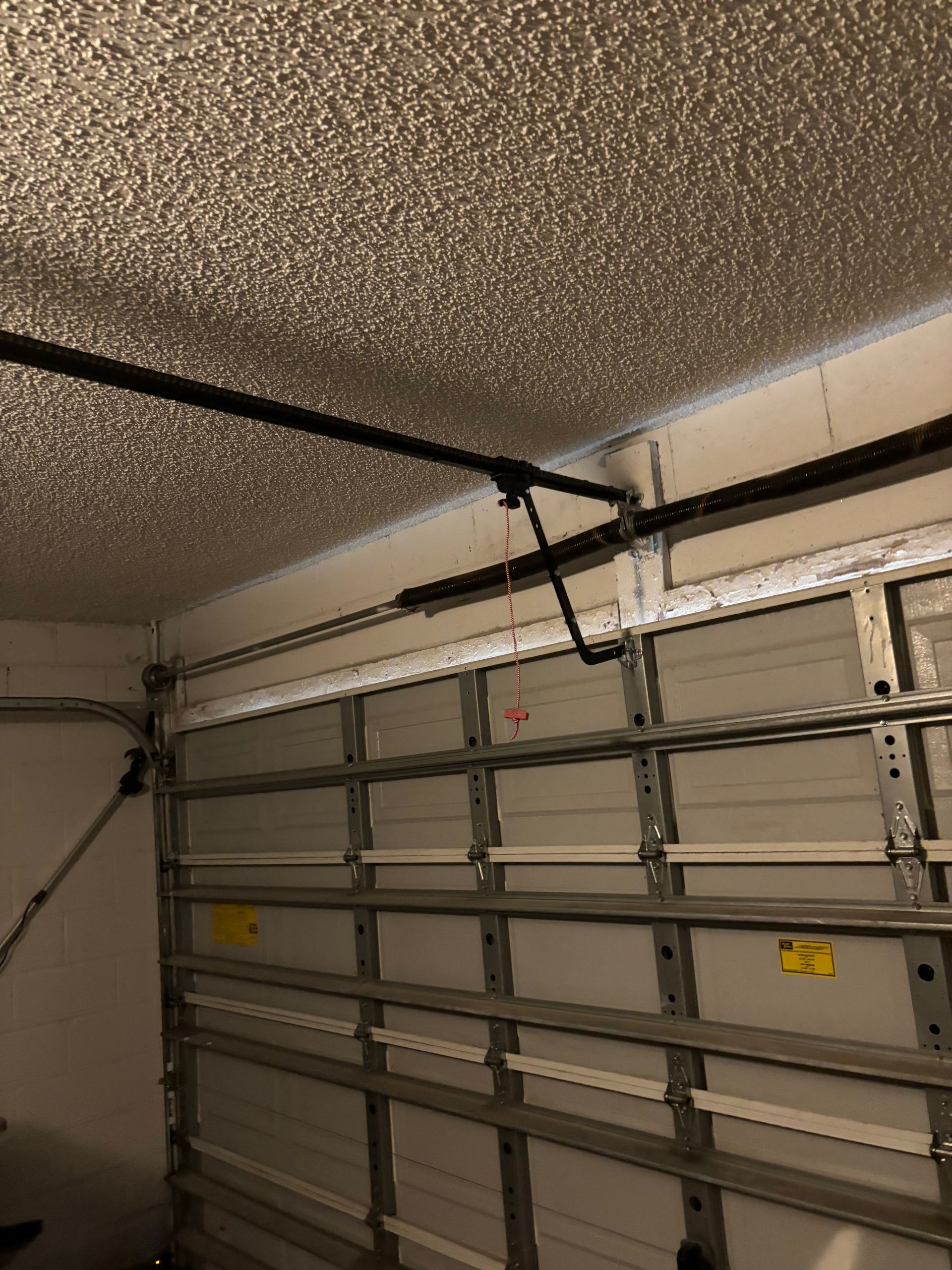 Garage interior with a closed white sectional door and ceiling-mounted opener rails