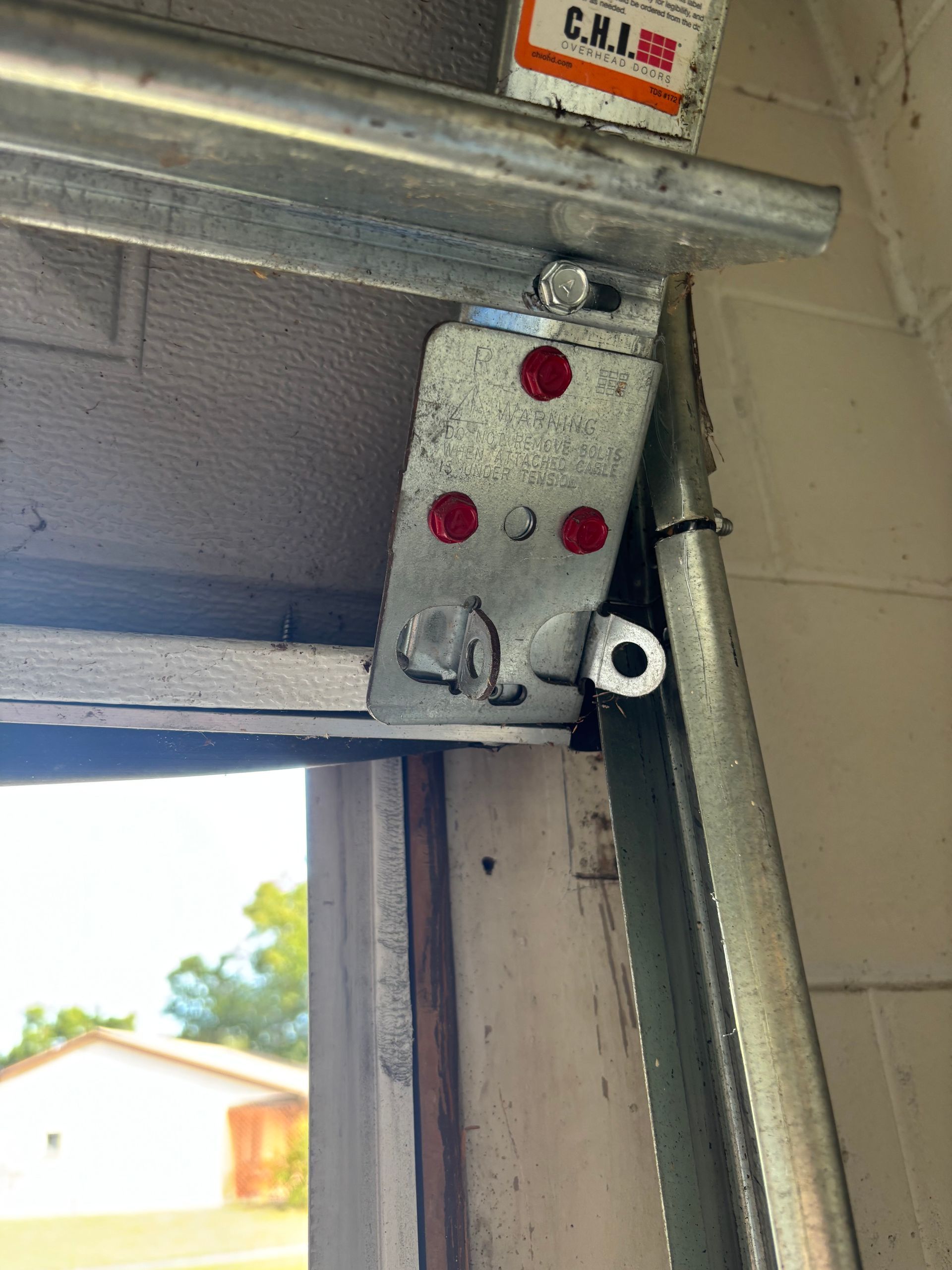 Close-up of a metal garage door hinge bracket with red markings on the frame.