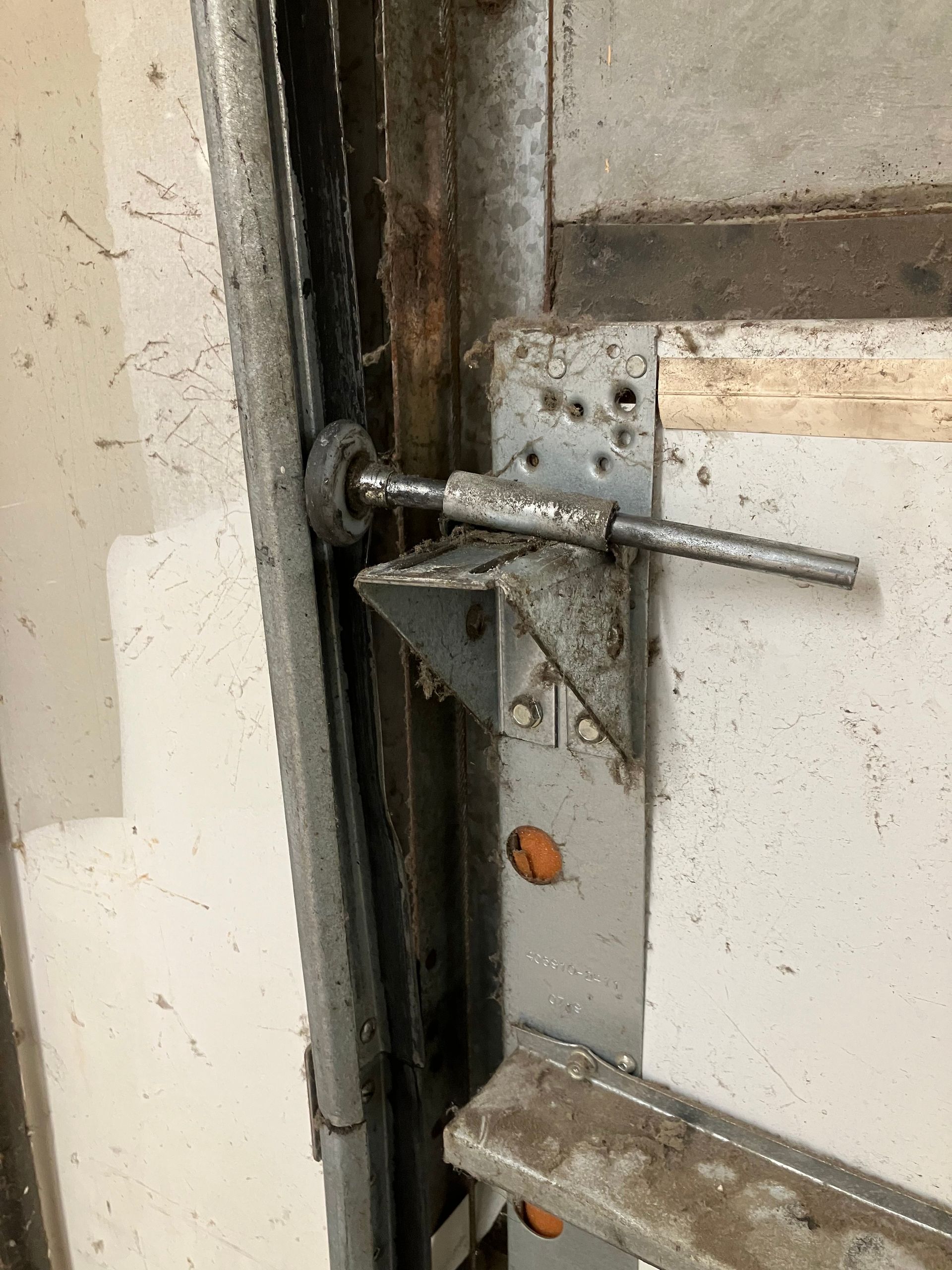 Close-up of a metal door latch and locking rod on a worn white door frame