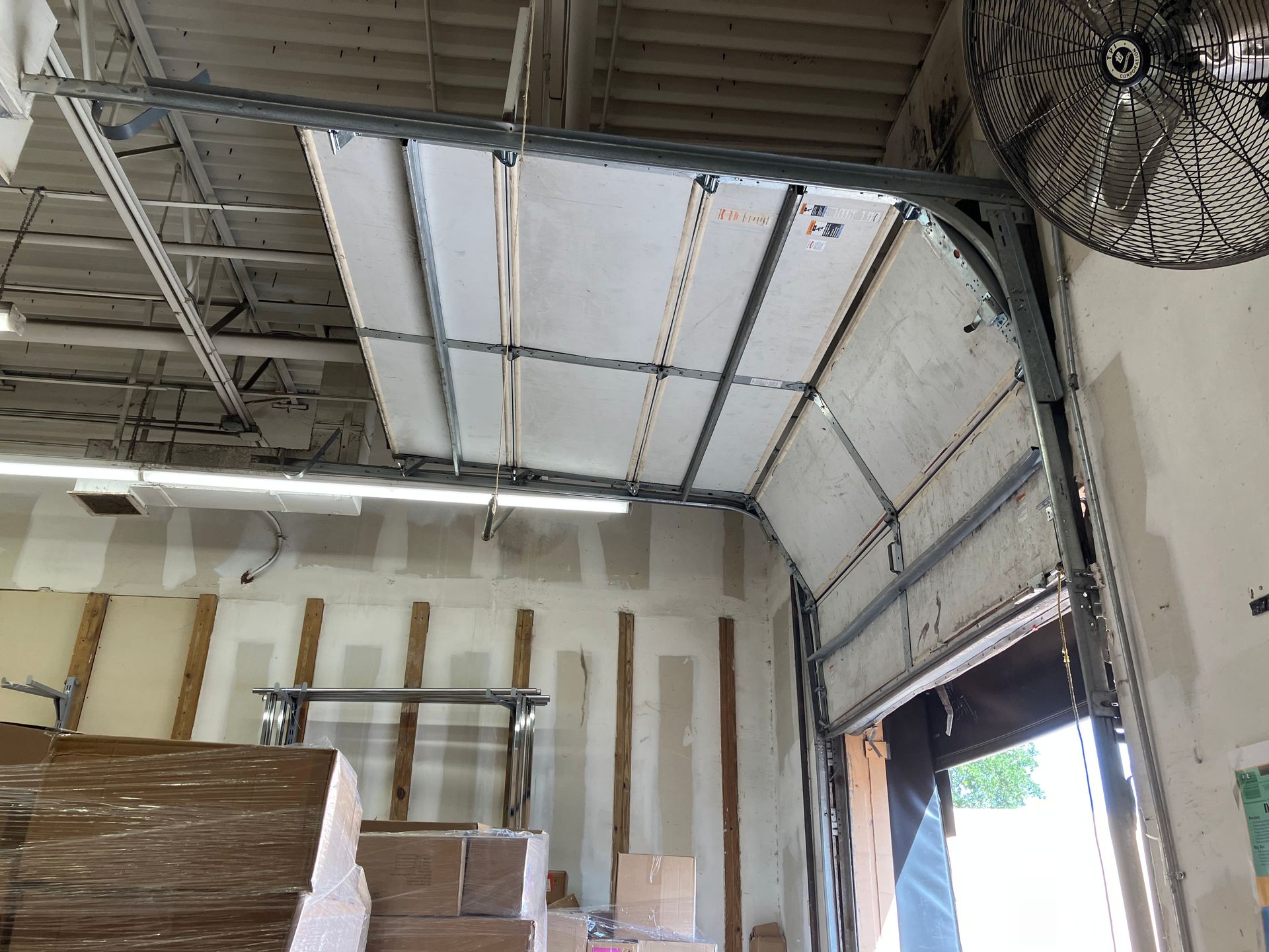 Industrial warehouse interior with stacked boxes, high metal ceiling, and an open loading bay door
