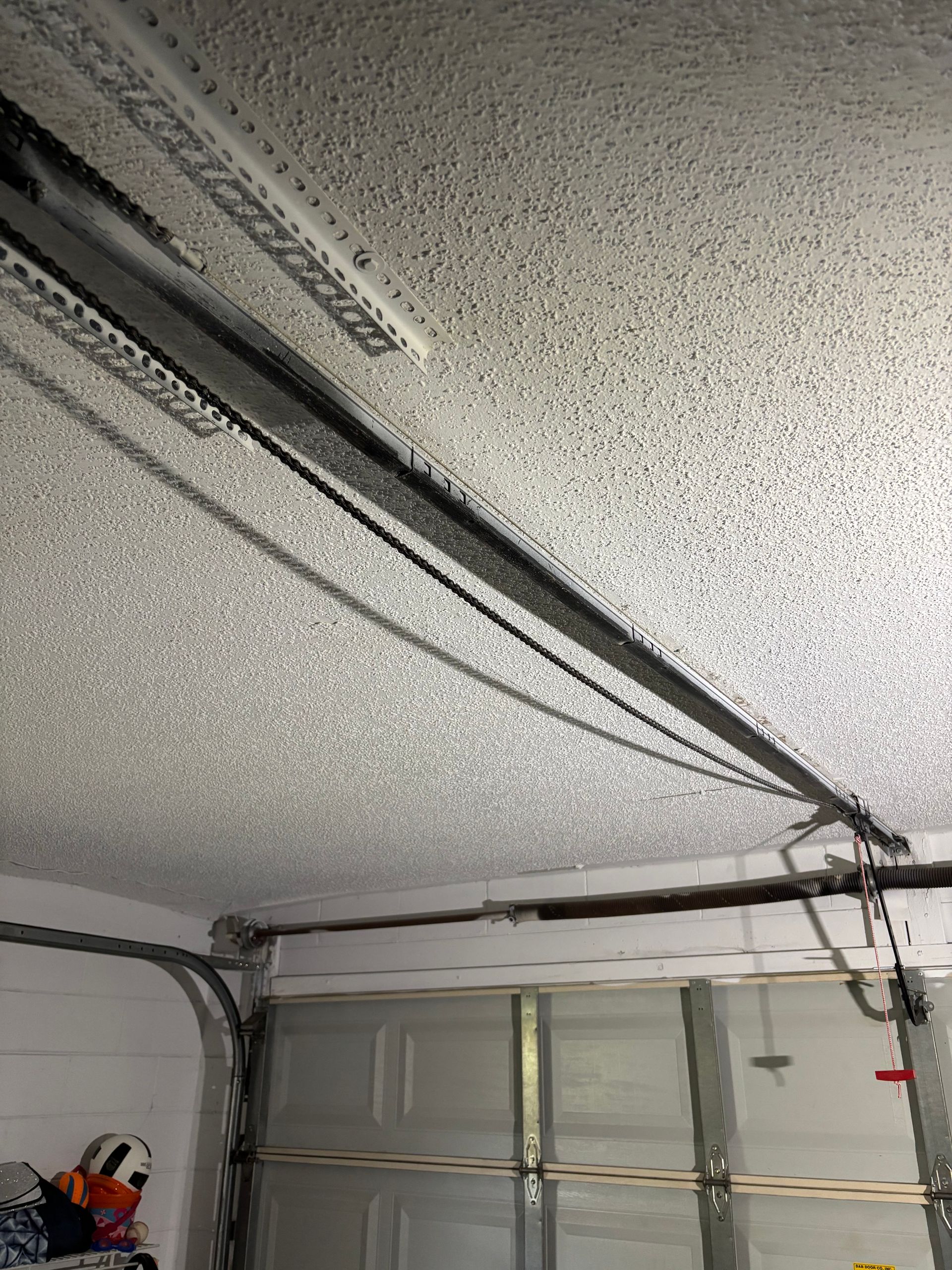 Garage ceiling with a cracked, sagging garage door track and opener rail above a closed door