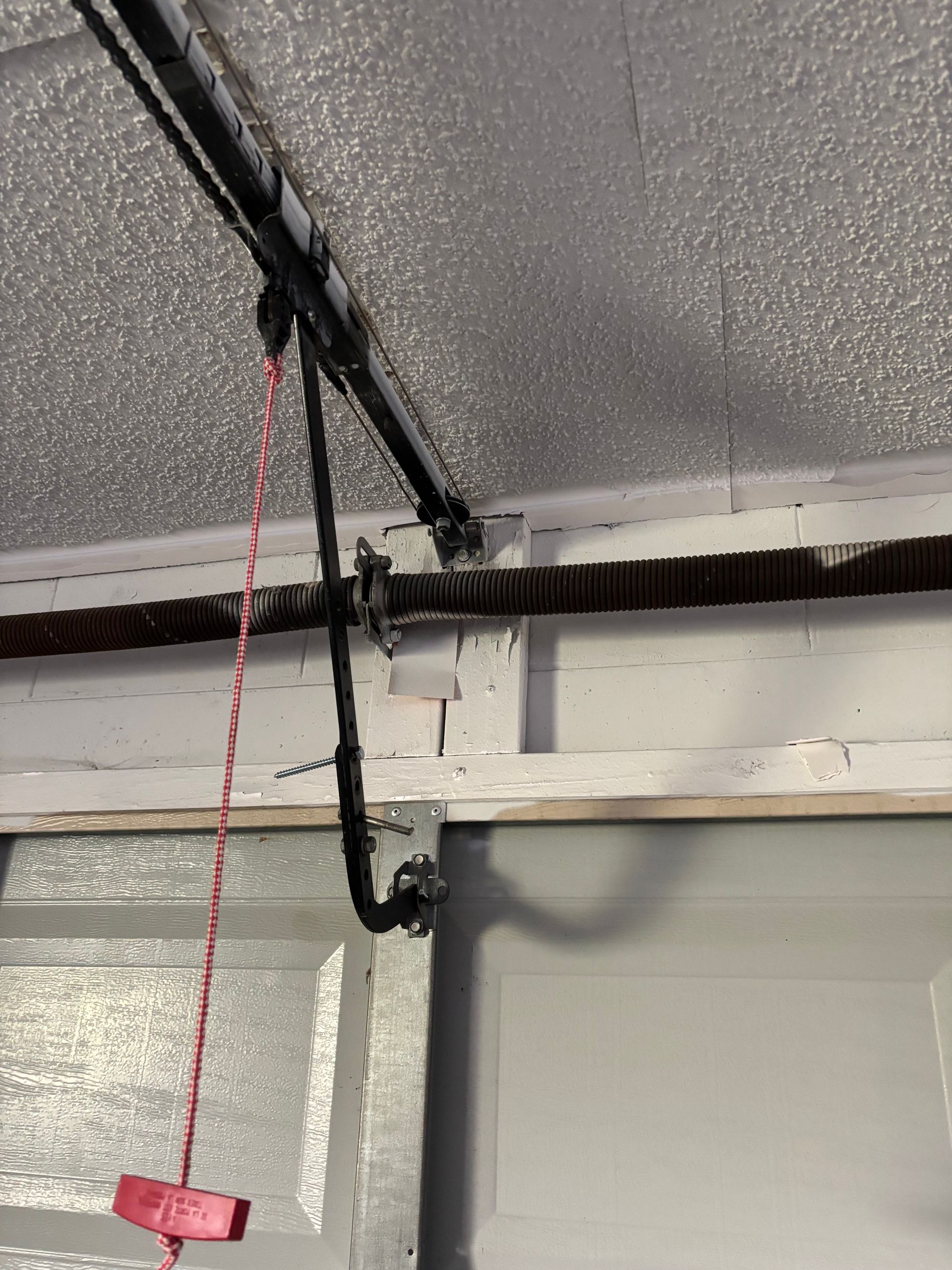 Garage door opener rail and red emergency release cord mounted near the ceiling