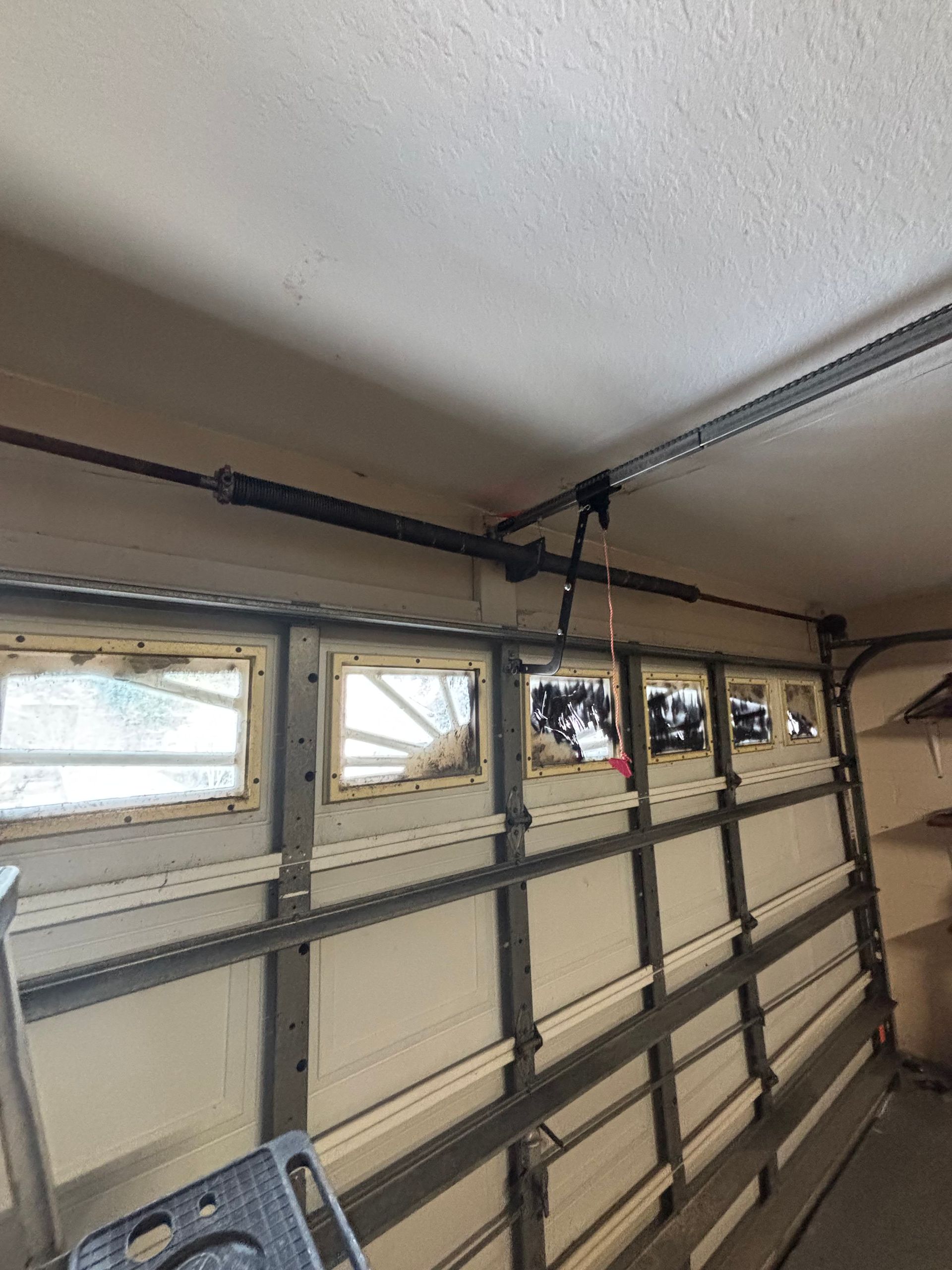 Interior of a garage door with metal tracks, windows, and overhead openers mounted near the ceiling