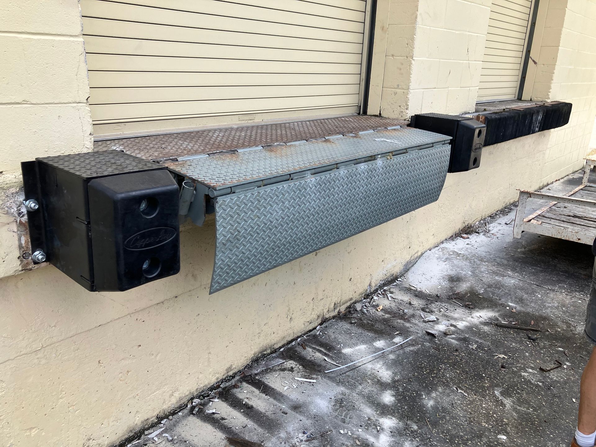 Black wall-mounted trays or ledges along a beige exterior wall with a shuttered window.