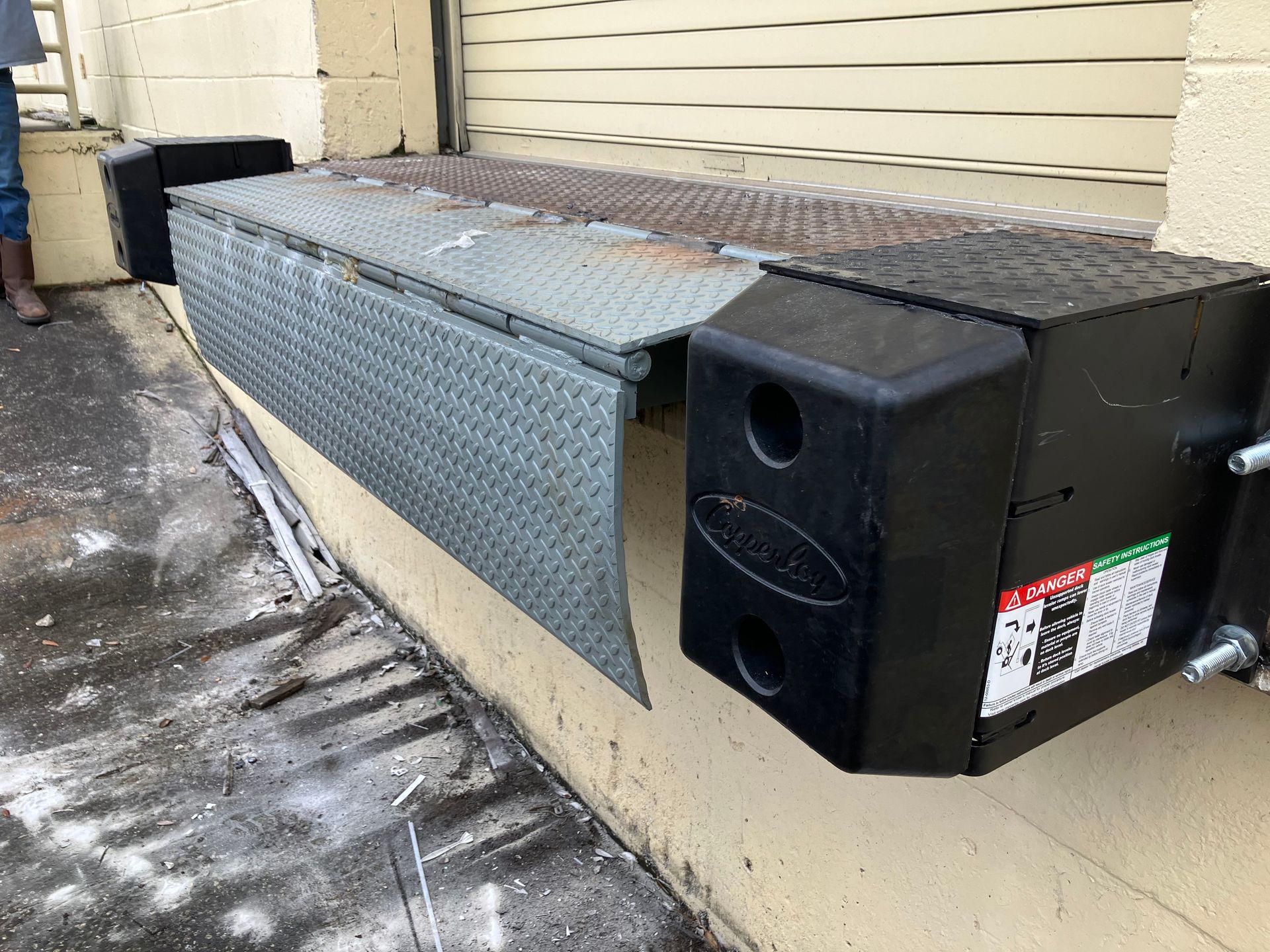 Black metal HVAC unit mounted on an exterior wall beside a side alley.
