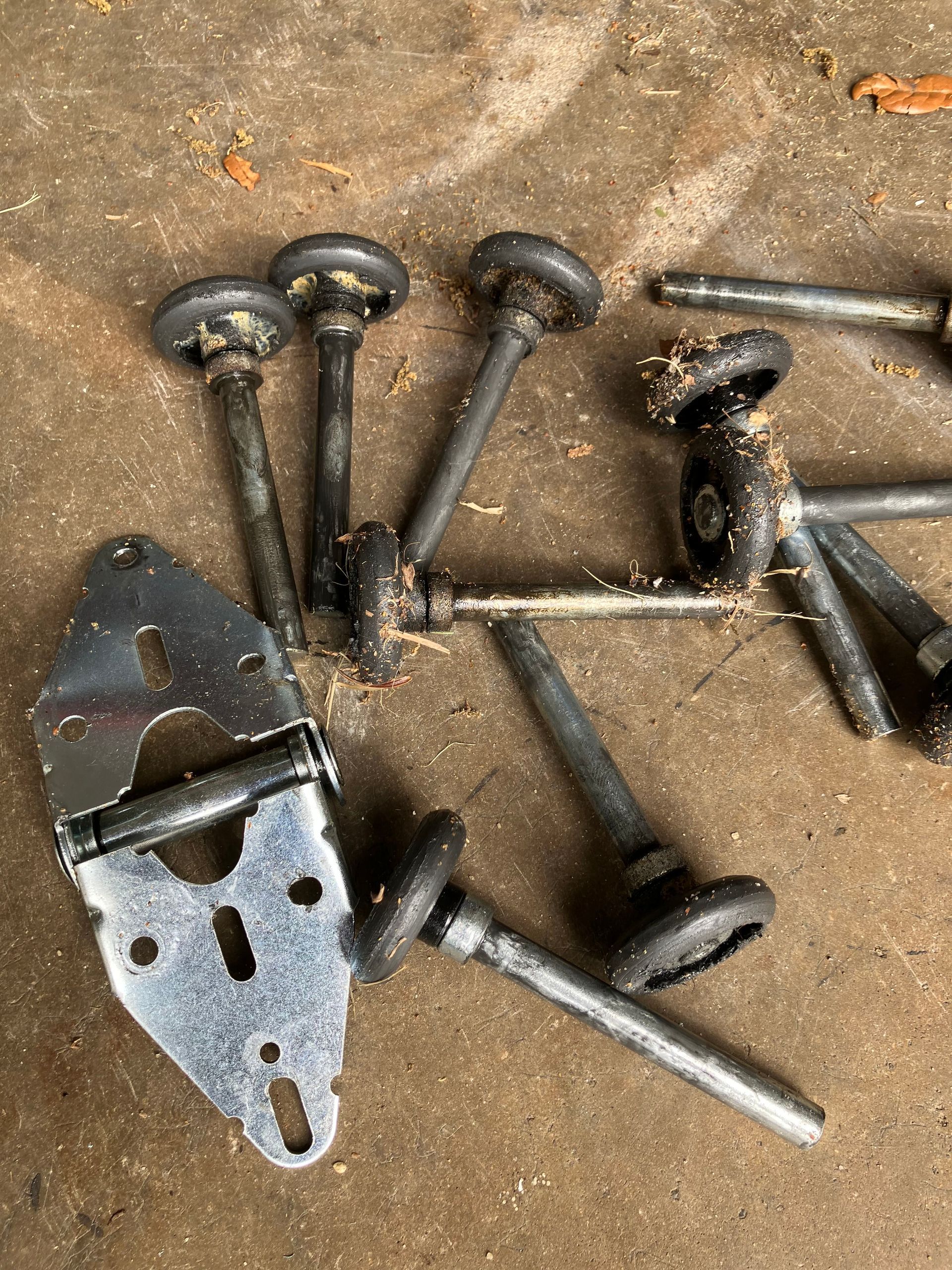 Scattered black metal bolts, screws, and a bracket on a dirty work surface