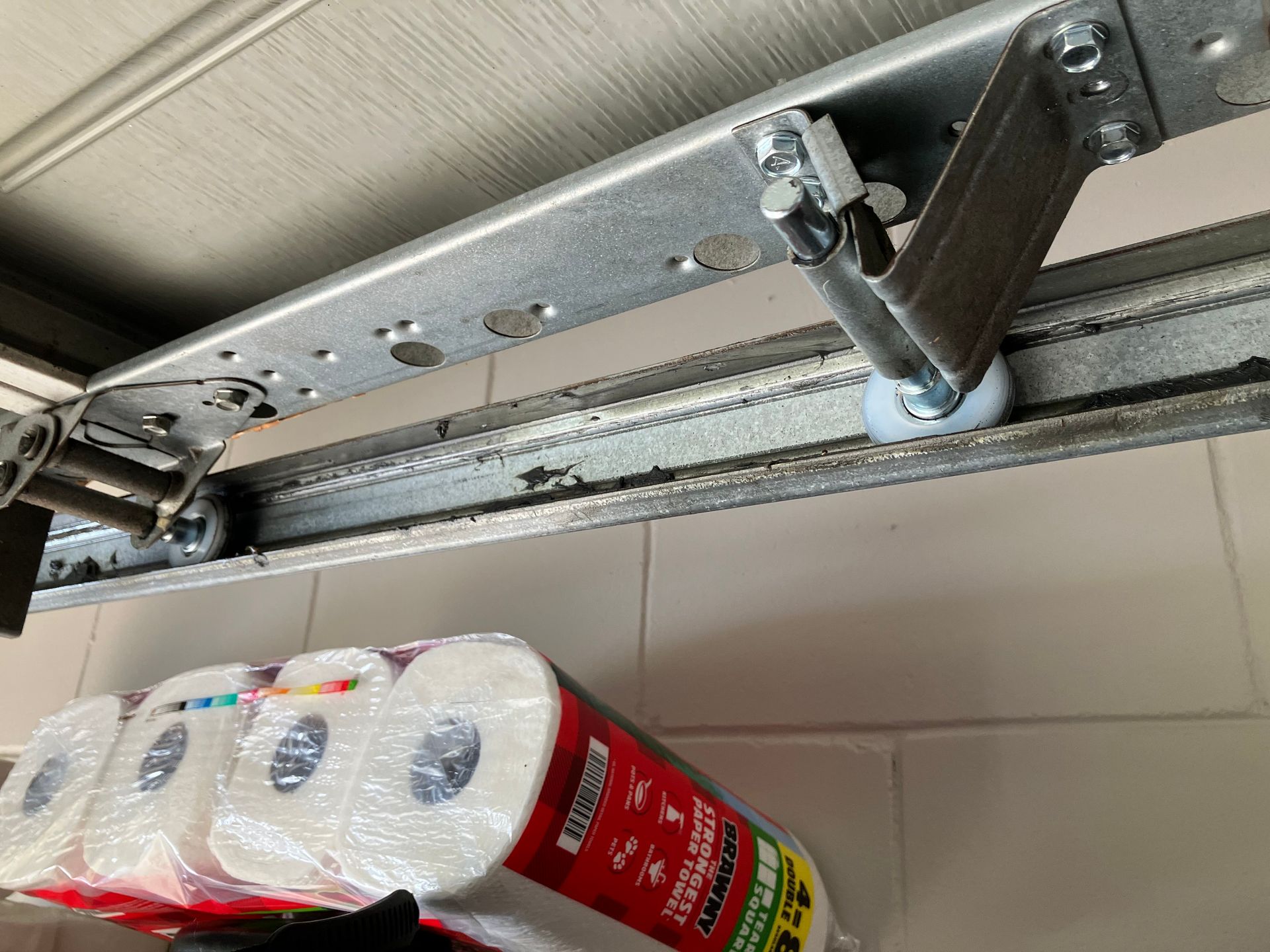 Garage door track with stacked paper towel rolls on the floor below.