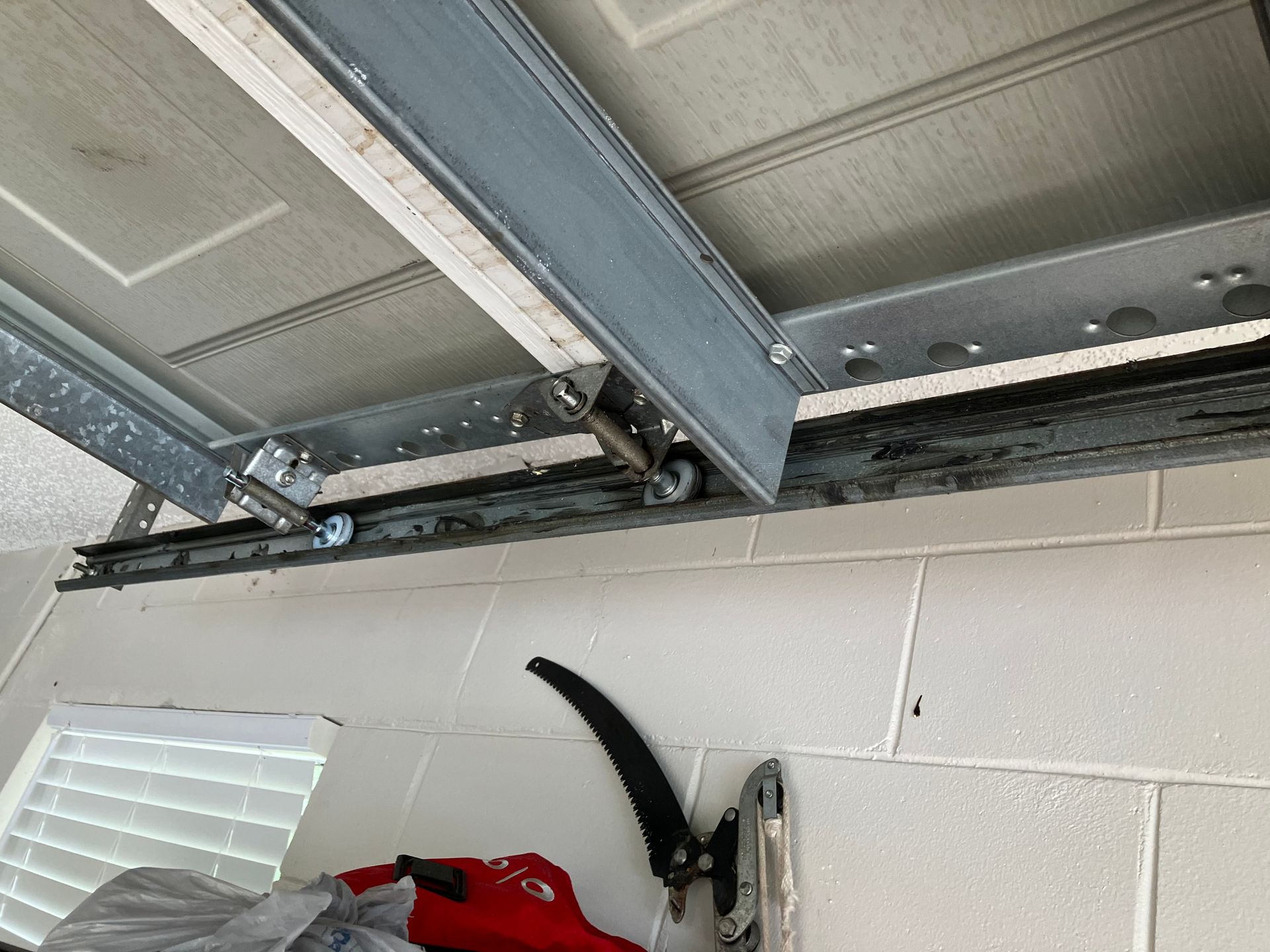 Garage ceiling with exposed metal tracks and a red hose reel mounted on a cinderblock wall