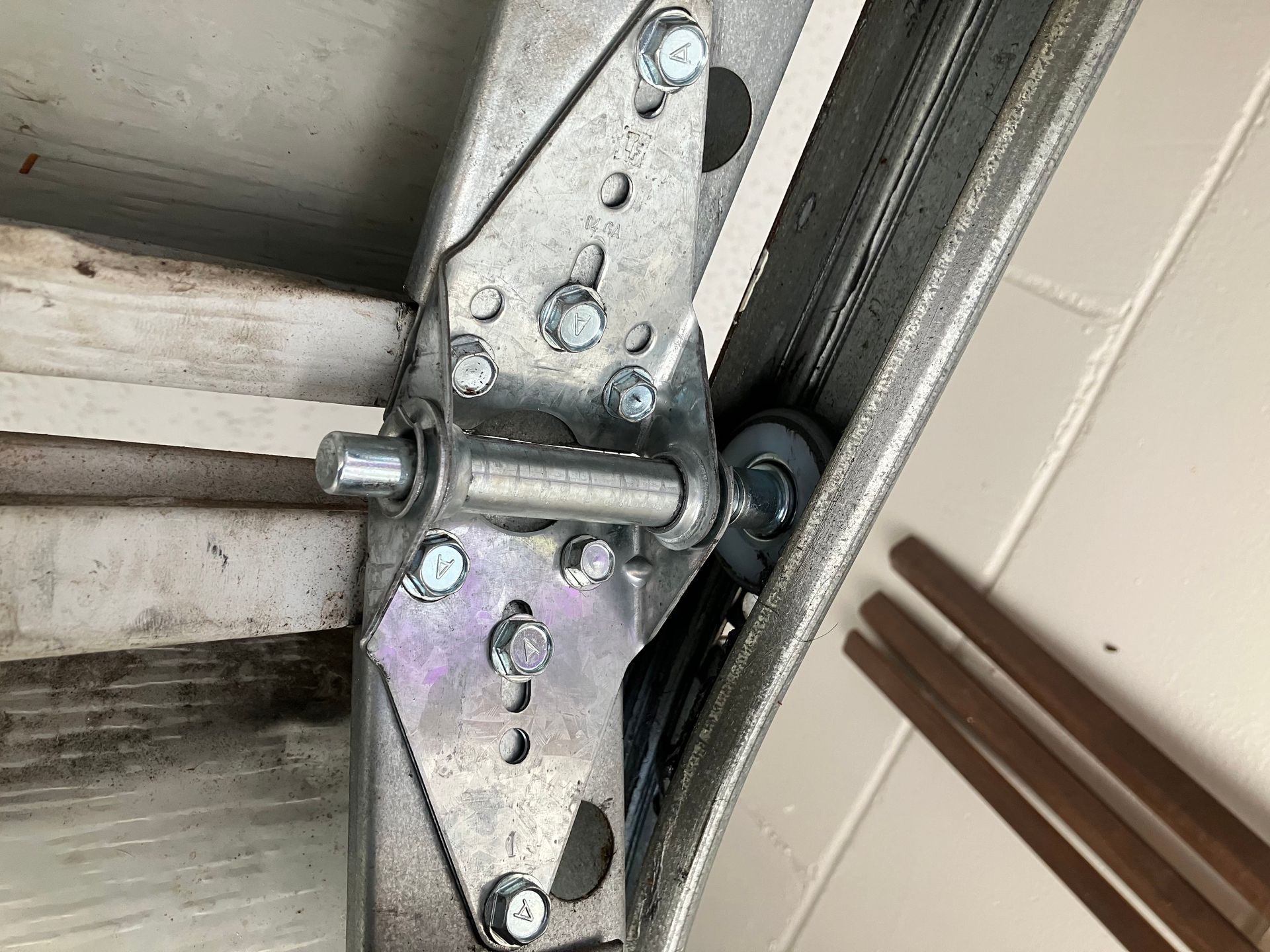 Close-up of a garage door hinge and roller assembly with metal track and bolts.