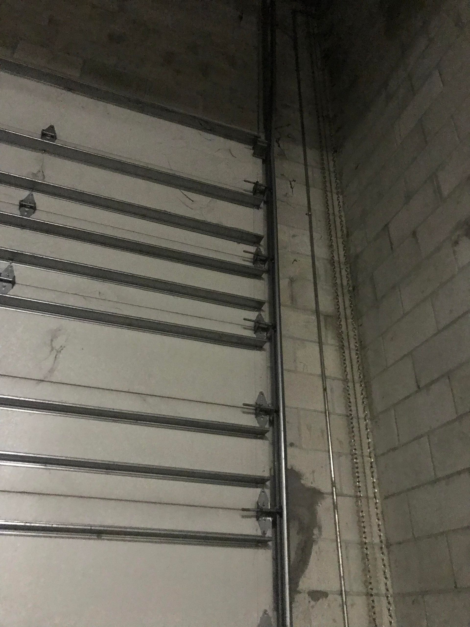 Industrial interior with a large metal door and concrete walls, viewed in dim light