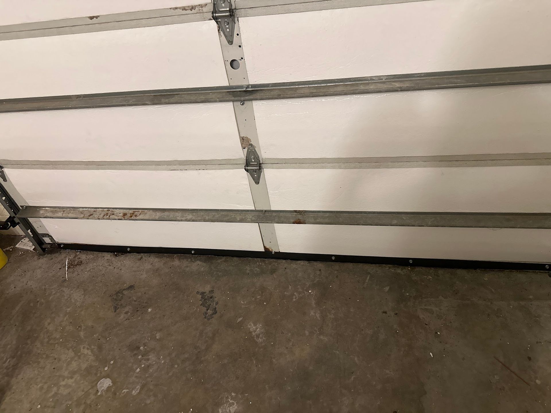 Interior view of a white garage door with horizontal panels and a concrete floor