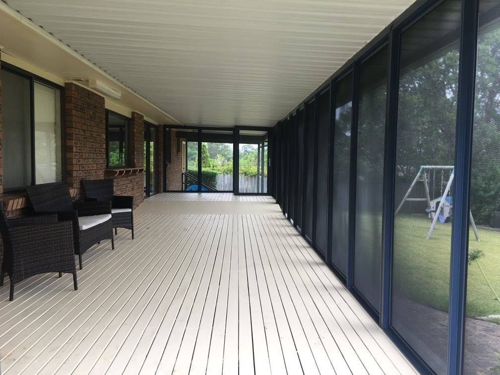 A screened in porch with chairs and a swing set