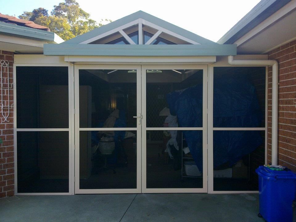 A screened in porch with a blue trash can in front of it