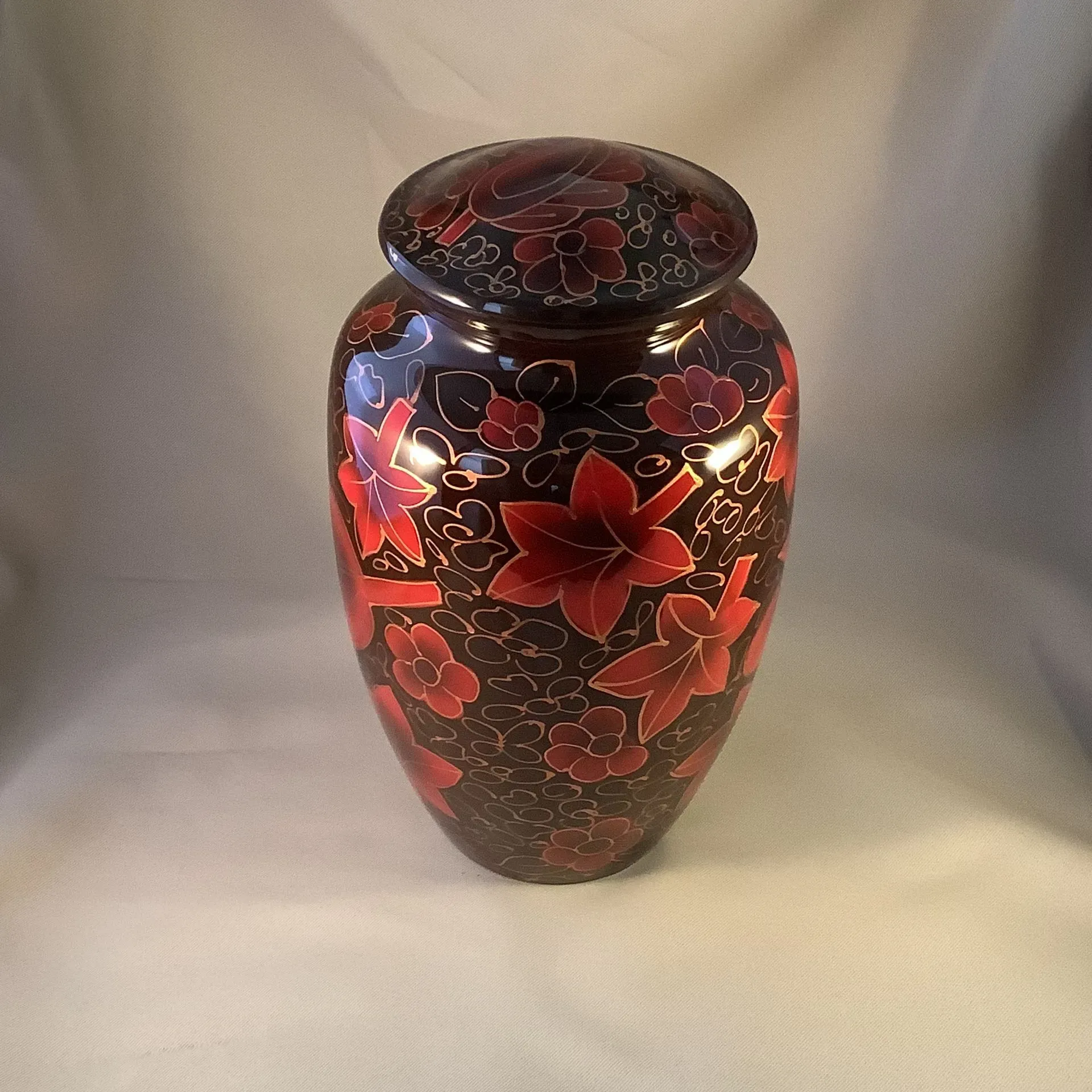 Glossy dark vase with red floral patterns on a light background