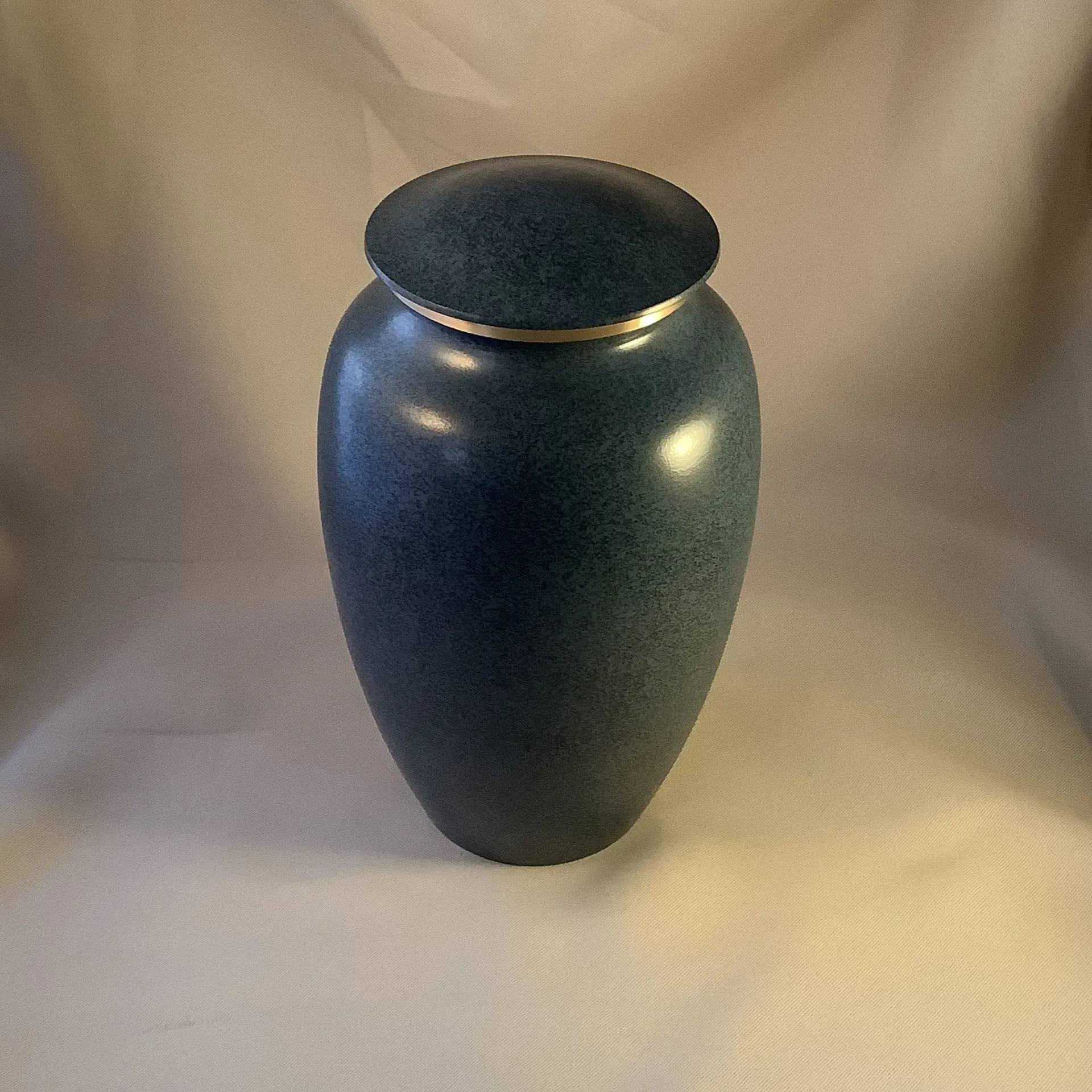 Dark blue ceramic urn with a lid, centered on a neutral beige background