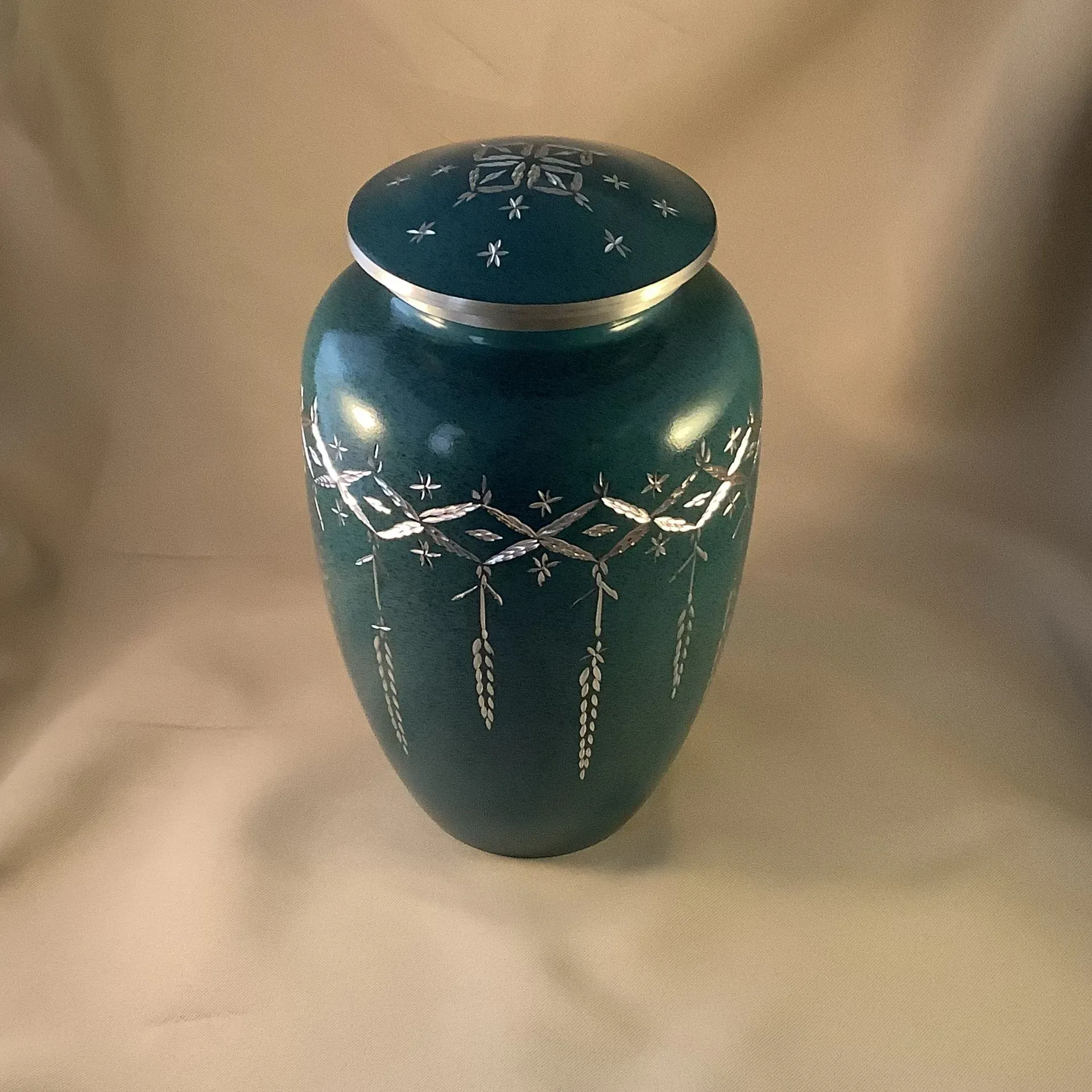 Blue decorative ceramic vase with silver accents on a beige background