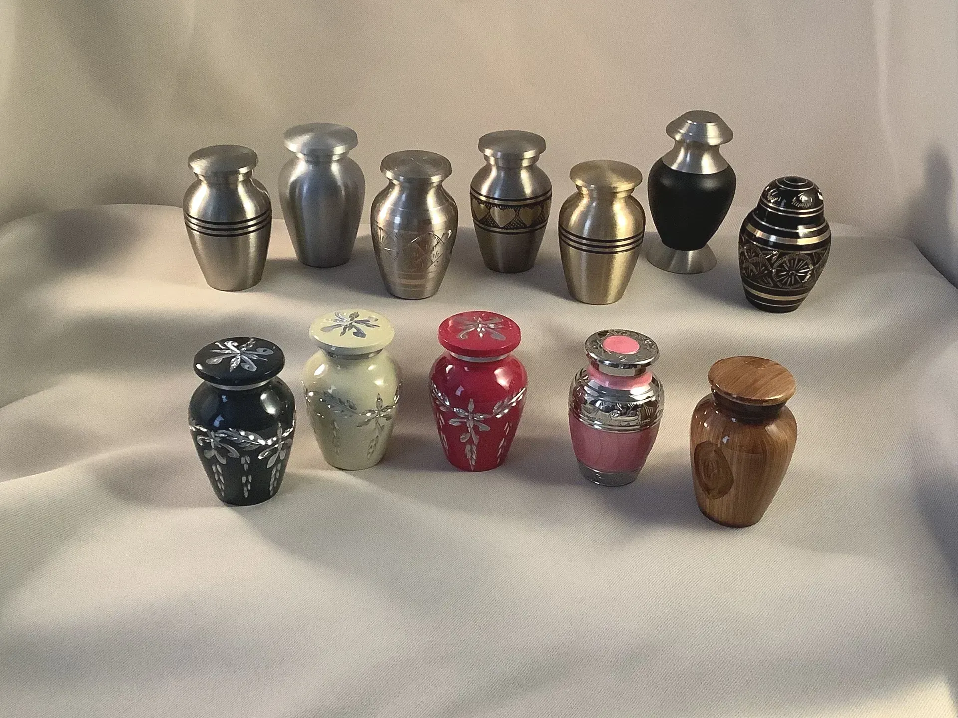 Small collection of colorful decorative urns and vases arranged on a white cloth.