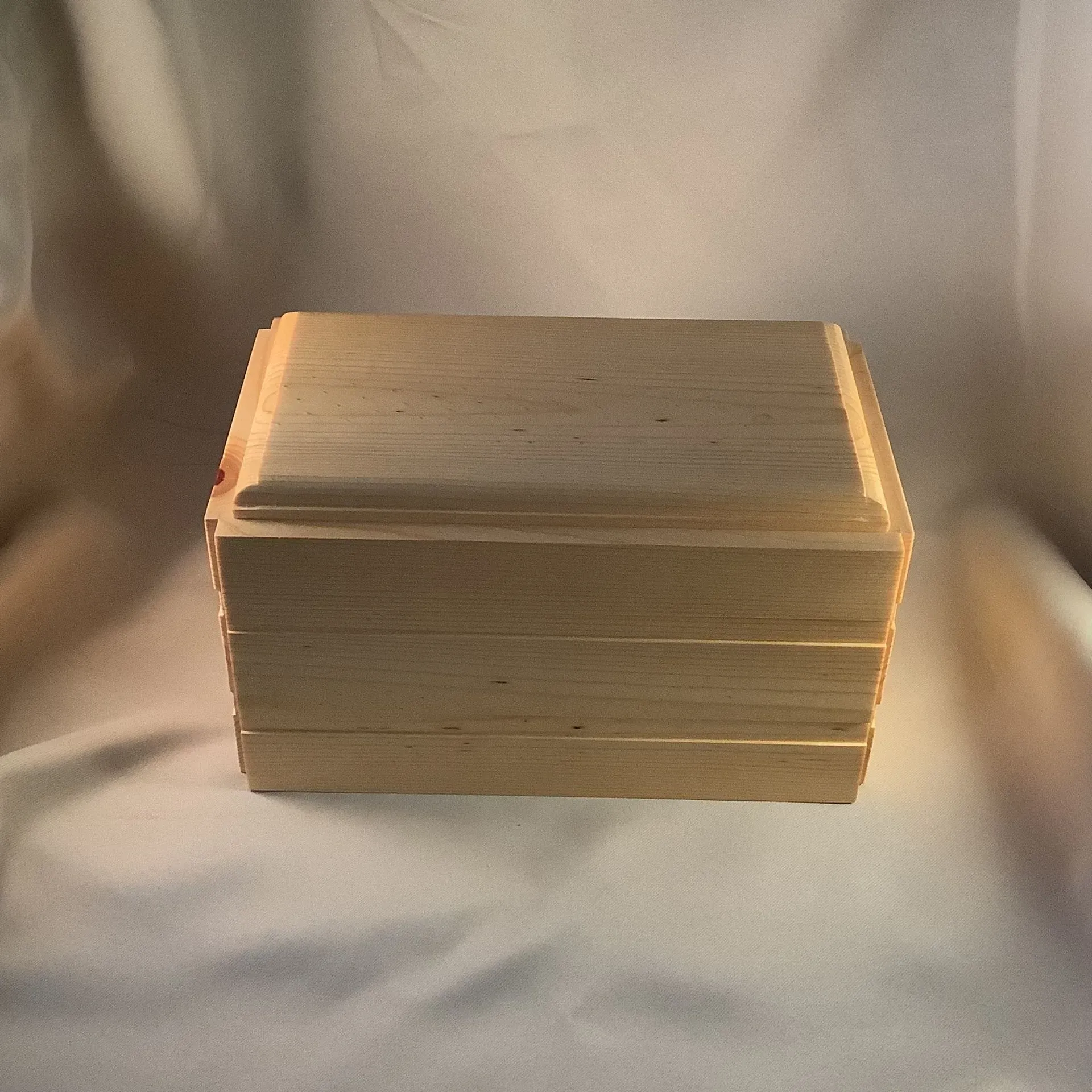 Small rectangular wooden box with a dark brown finish on a light fabric background
