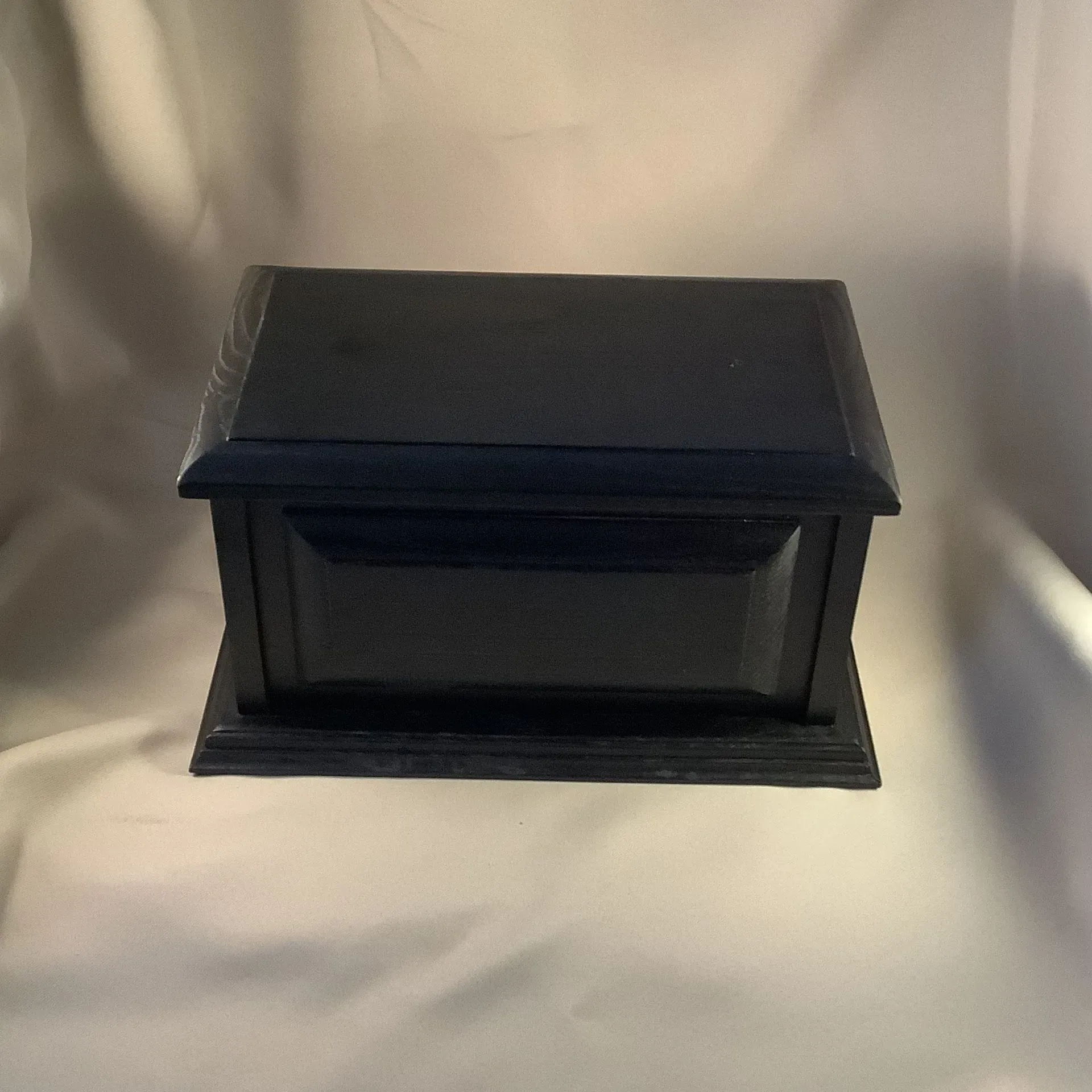 Black rectangular wooden box on a light fabric background.