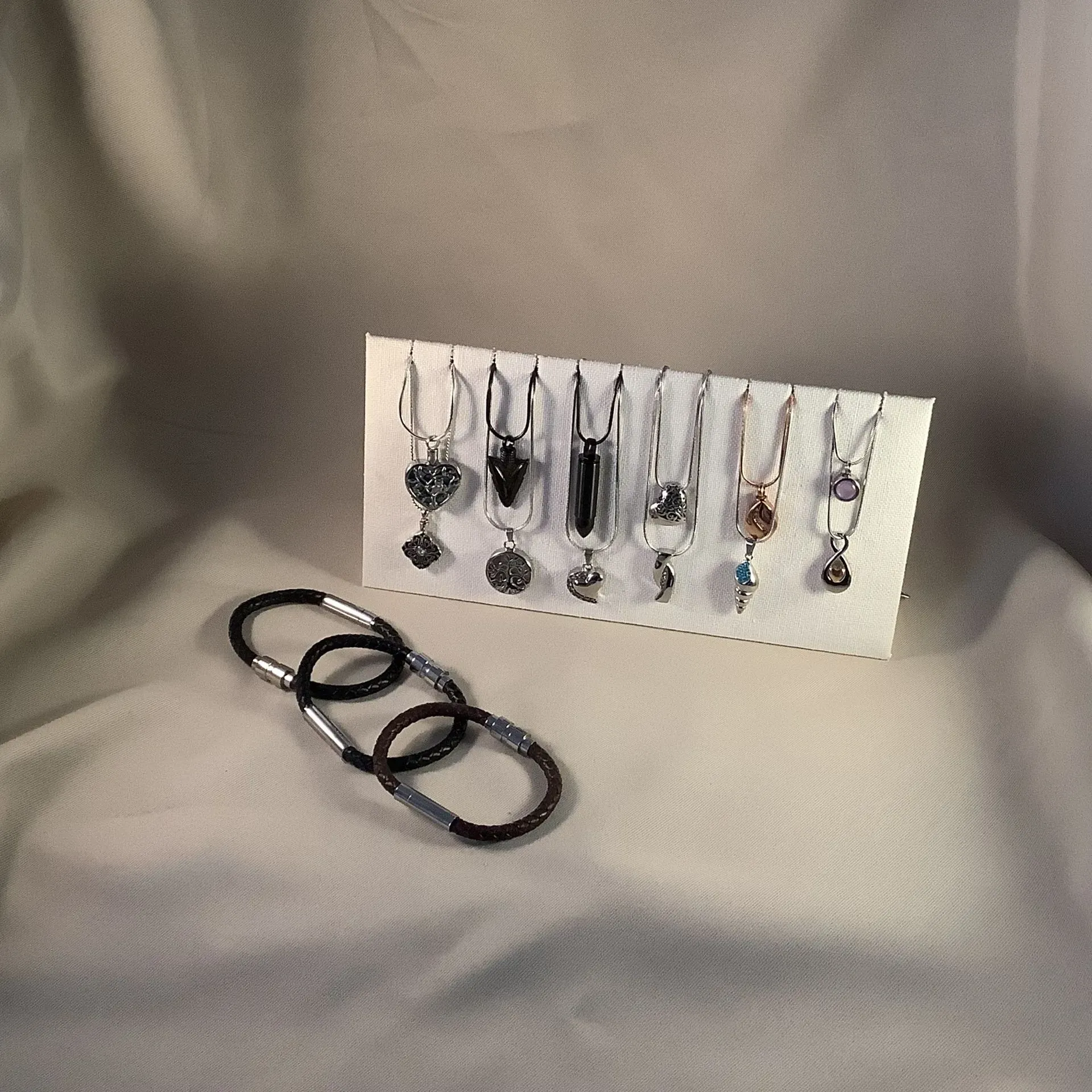 Assorted necklaces on display card with three black bangles on a gray backdrop