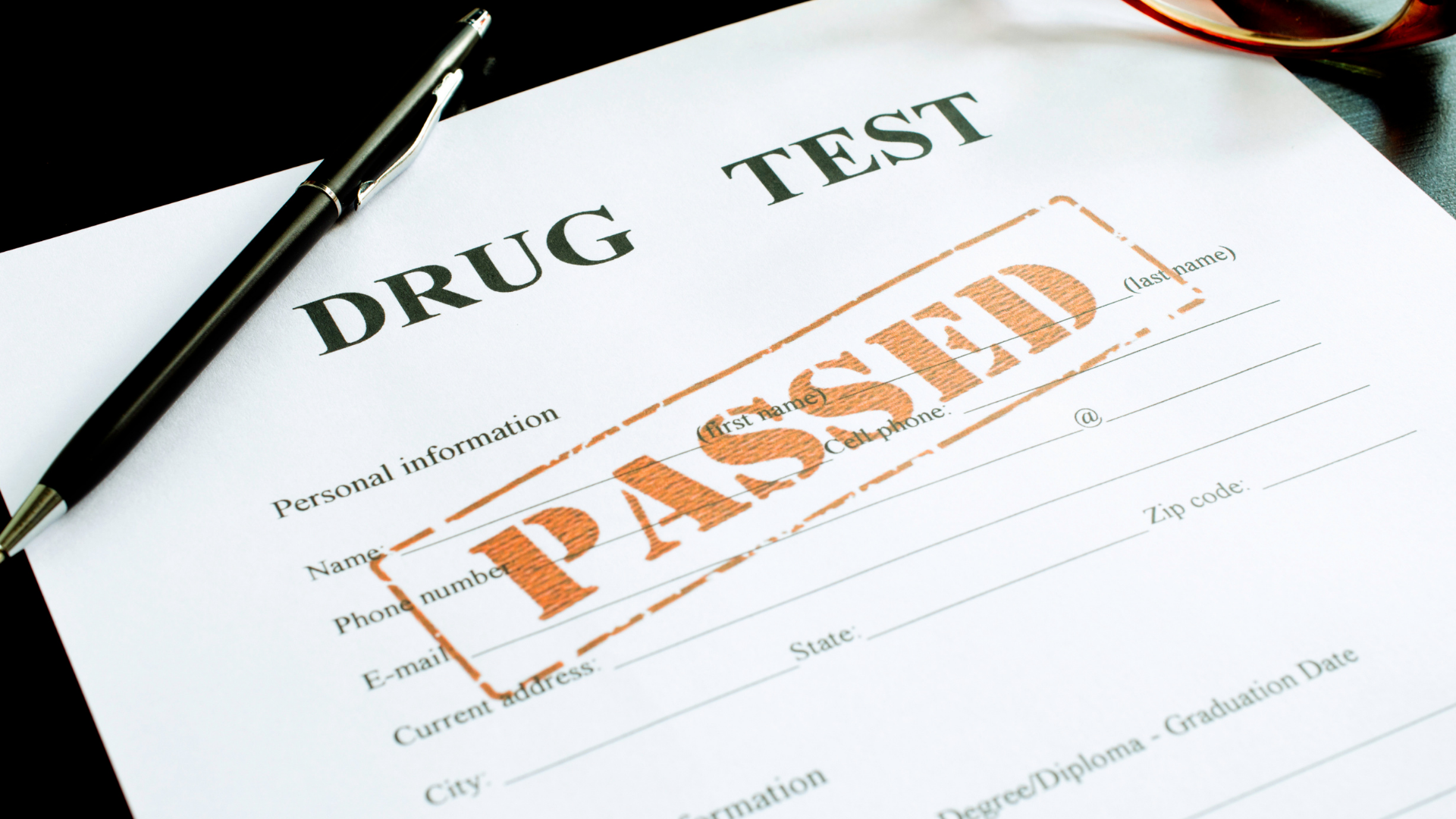 Drug test form with a large orange “PASSED” stamp beside a pen.