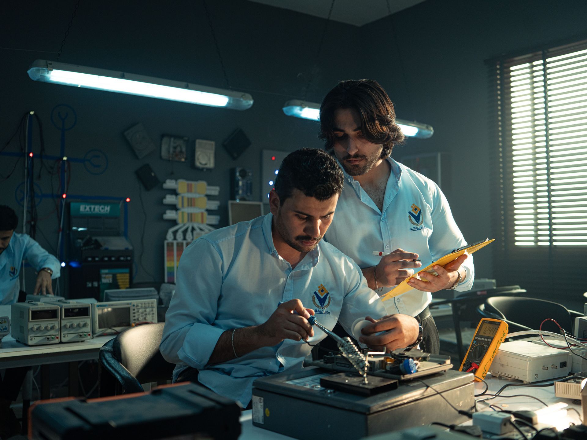 Two engineers working on electronic hardware at a lab bench, the kind of niche technical talent rare