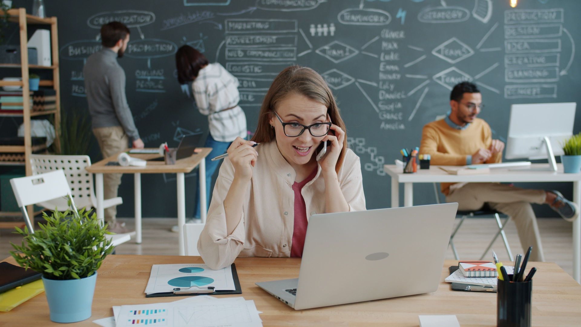 Busy corporate recruiter on the phone at her laptop while juggling a heavy load of open requisitions