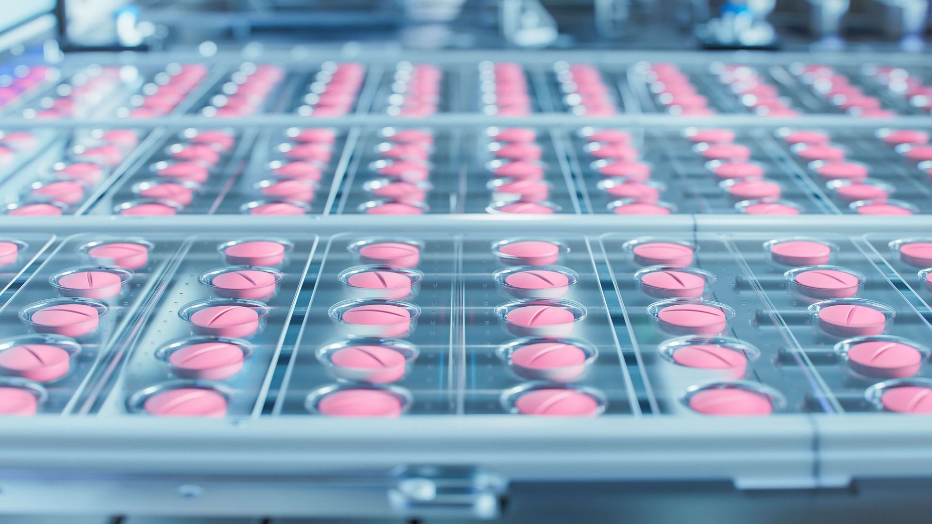 Pink pills in blister packs on an automated production line.
