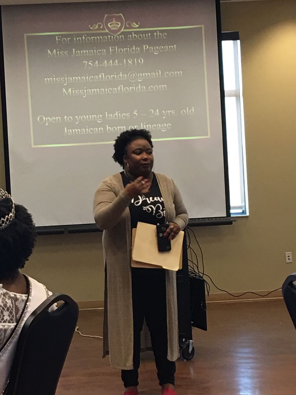 A woman is standing in front of a projector screen giving a presentation.