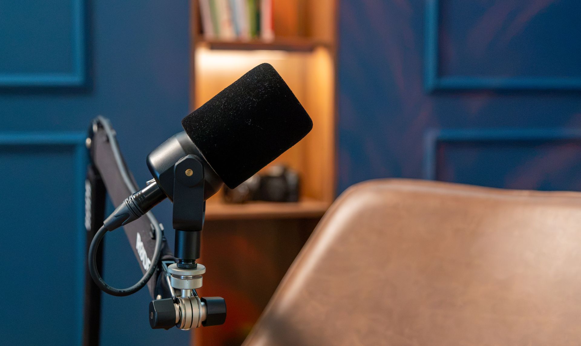 Professionele podcastmicrofoon op een verstelbare arm naast een fauteuil in de videopodcaststudio van FPS Media.