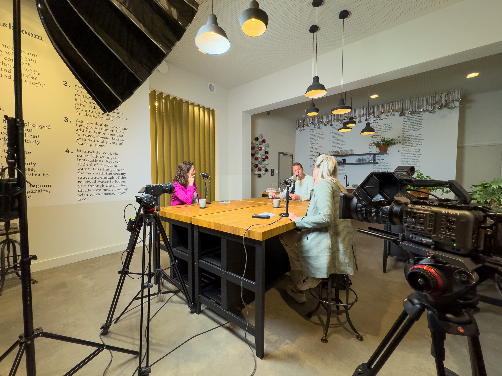 Drie mensen aan een tafel die een video opnemen.
