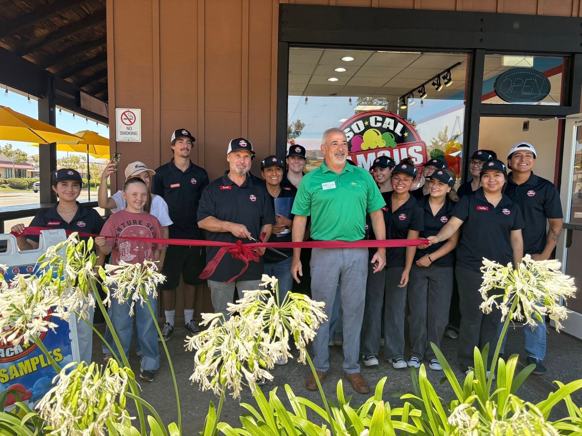 A group of people standing outside a So-Cal Famous shop during a ribbon-cutting ceremony.