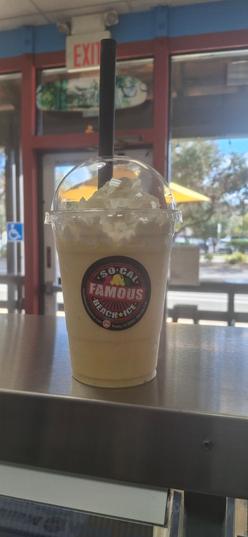 A plastic cup filled with a light-colored blended drink topped with ice, featuring a 