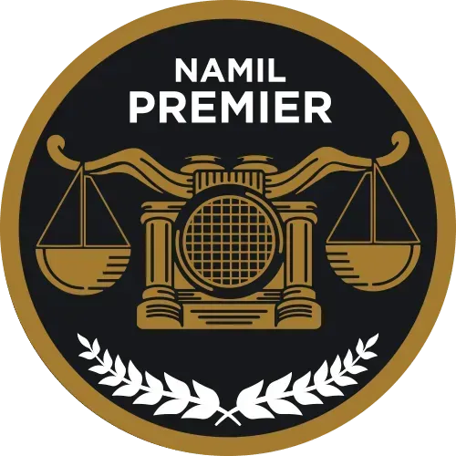 NAMIL Premier logo: gold scales of justice above a gold and brown stylized building; black background, gold border, laurel wreath.
