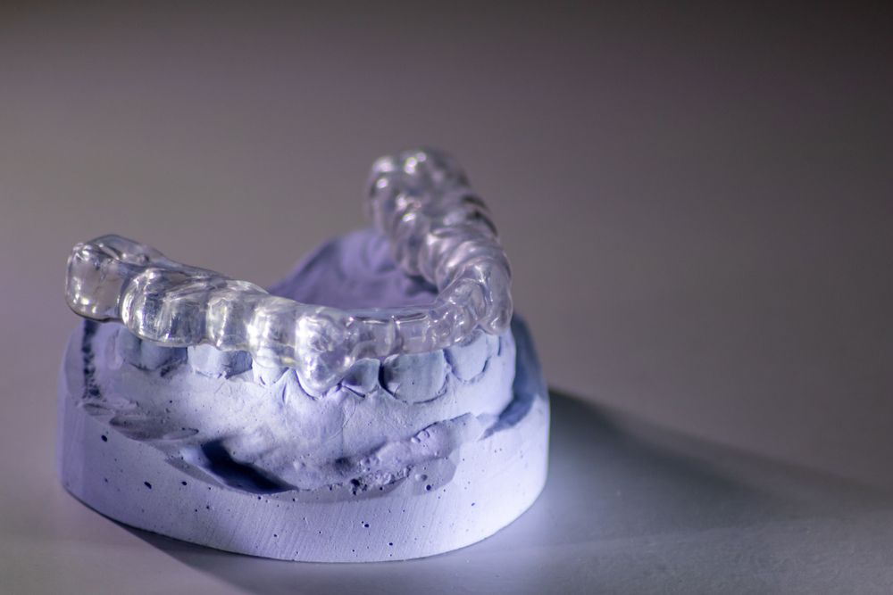 A model of a person 's teeth with a clear retainer on it.
