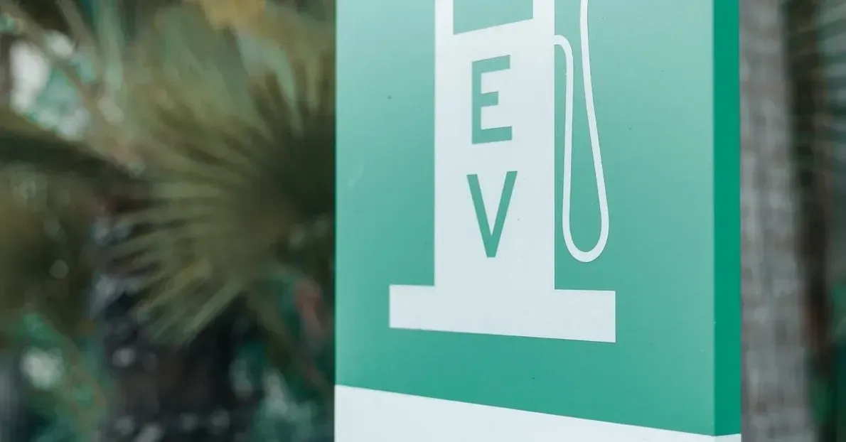 A teal sign features a white icon of an electric vehicle charging station with the letters